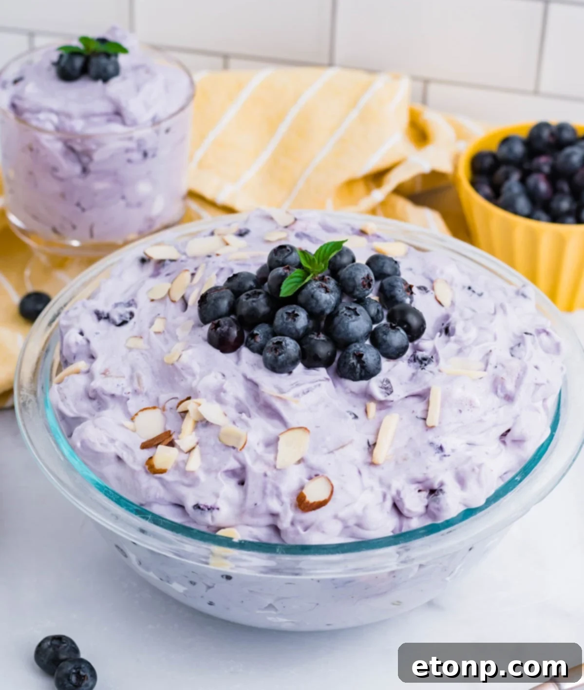 Blueberry Fluff Salad in a clear glass serving bowl topped with blueberries and chopped almonds