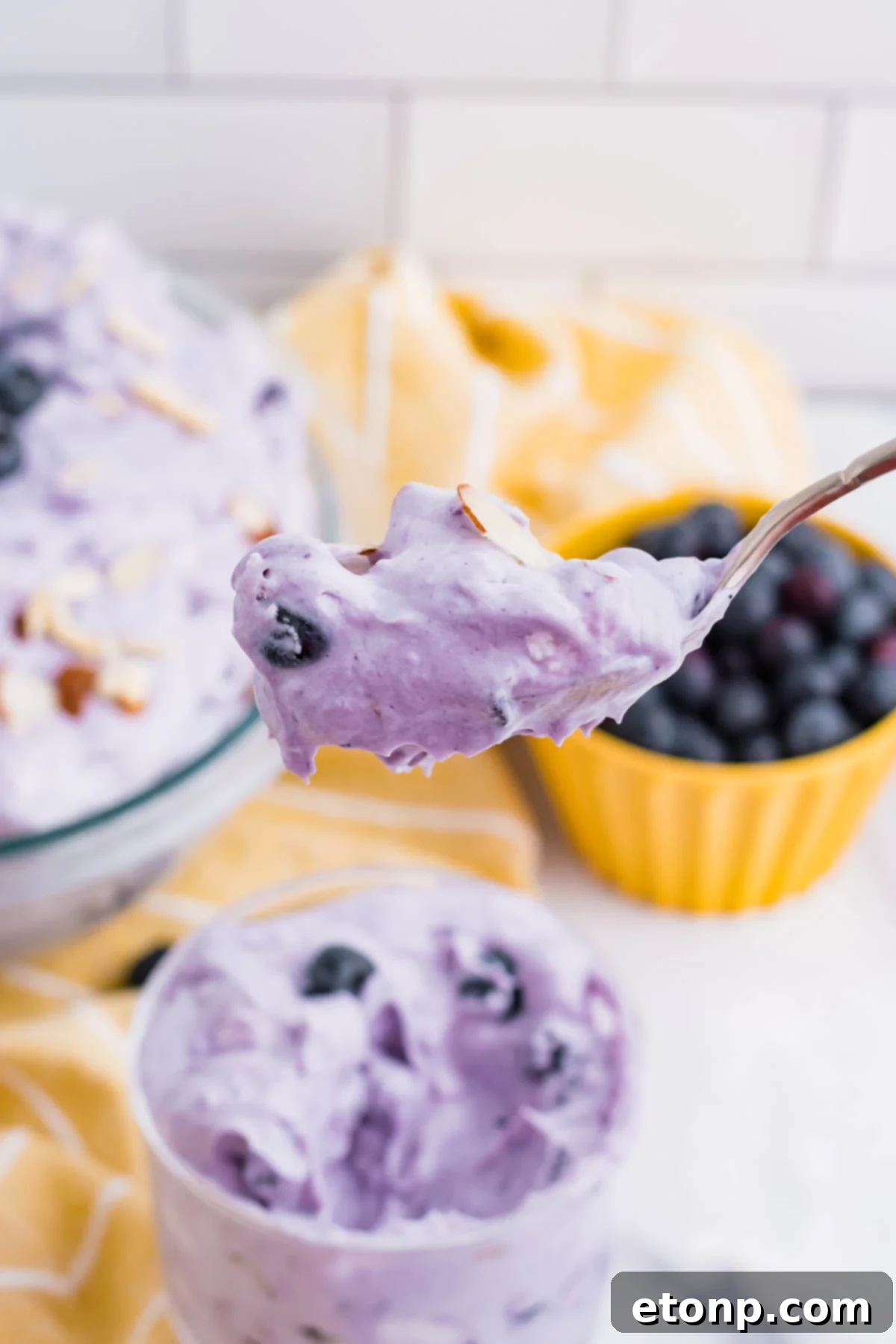 Blueberry Fluff Salad in a clear glass mini trifle with a spoon lifting up a big bite