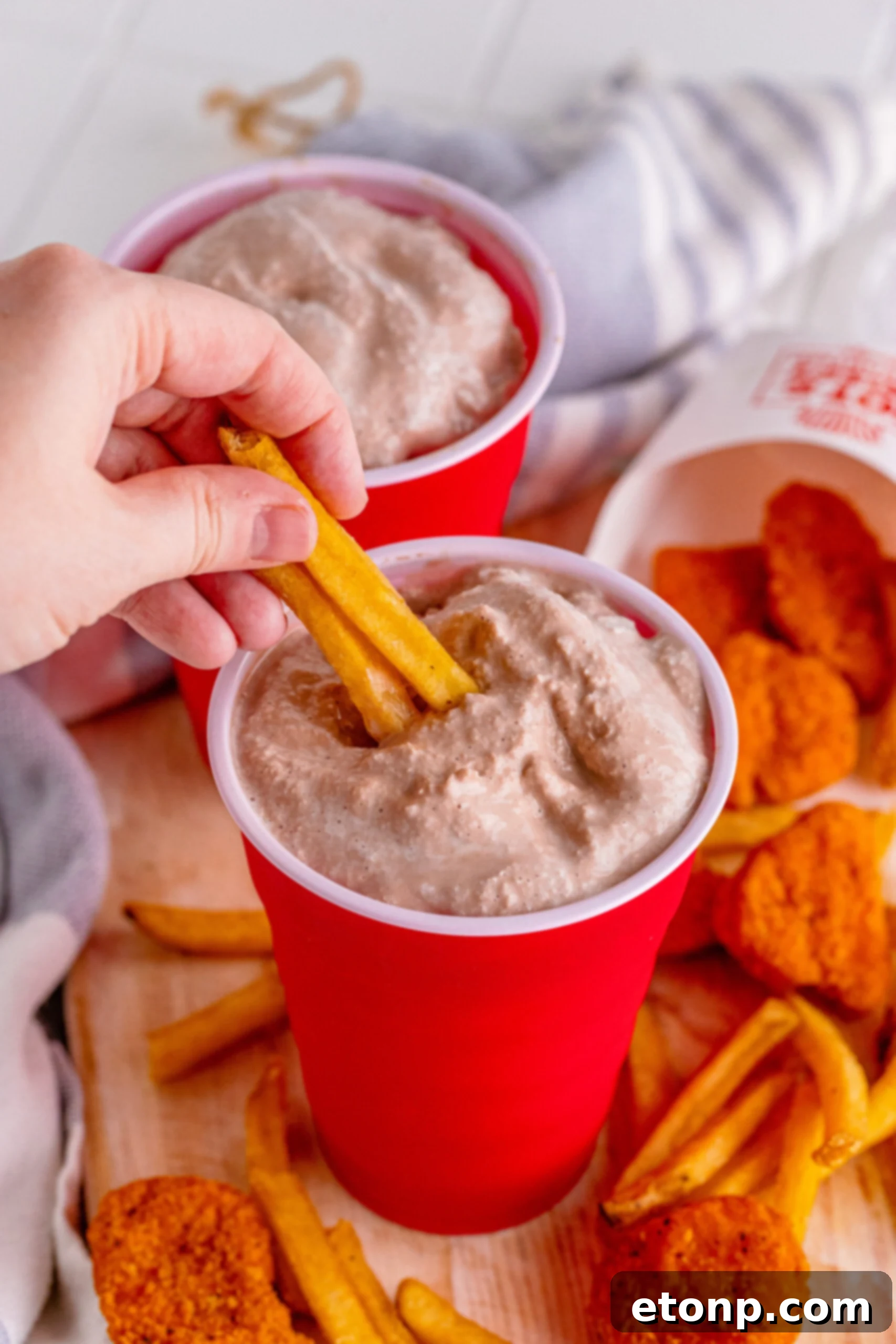 Homemade Wendy's Frosty in a red solo cup with fries being dipped into it, highlighting the classic pairing.