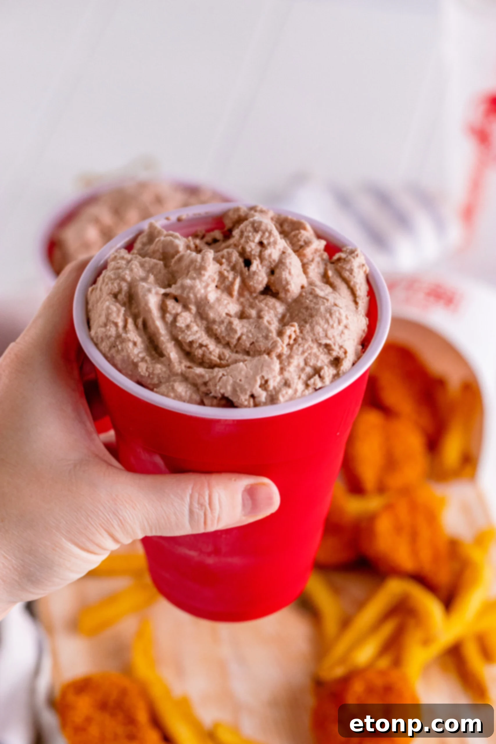 A homemade Wendy's Frosty in a red solo cup, held up against a blurred background, showcasing its rich texture.