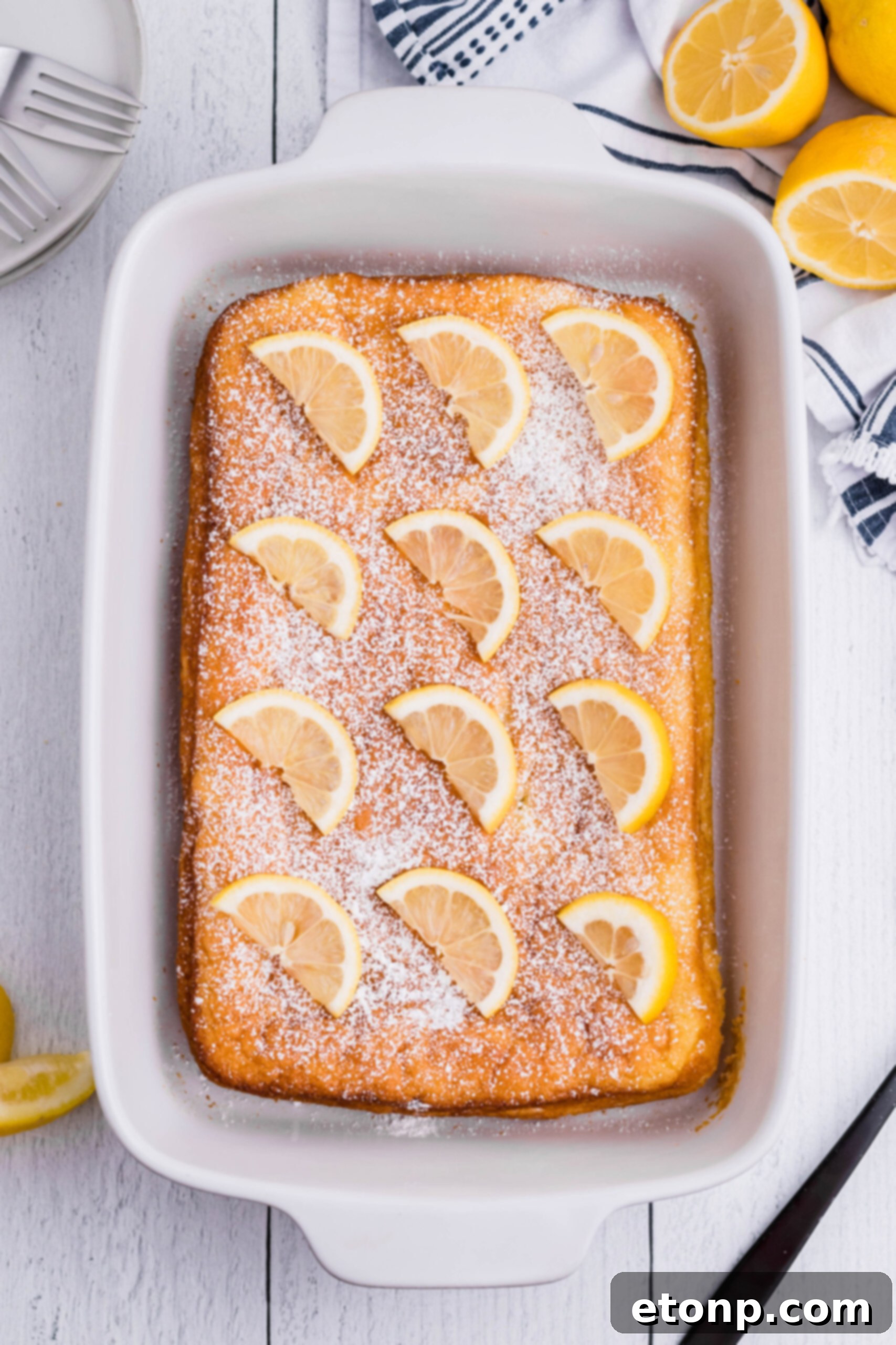 Overhead shot of freshly baked 2-Ingredient Lemon Bars, still uncut in a pristine white baking pan, promising deliciousness