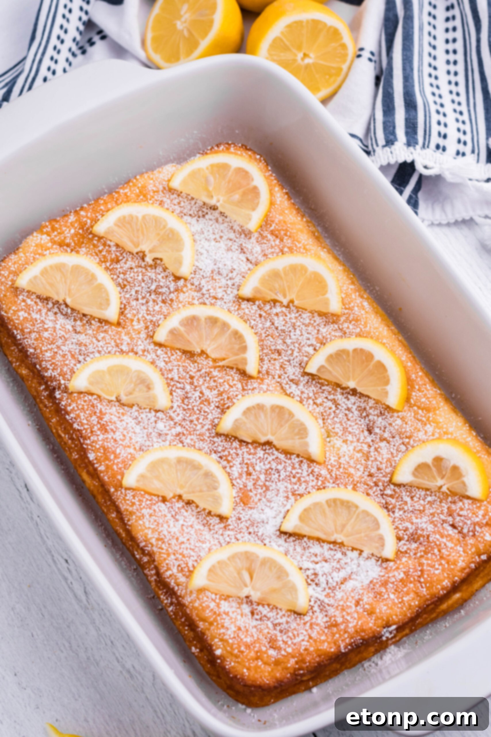 Uncut 2-Ingredient Lemon Bars, showing a uniform texture in a white baking pan, tempting to be sliced