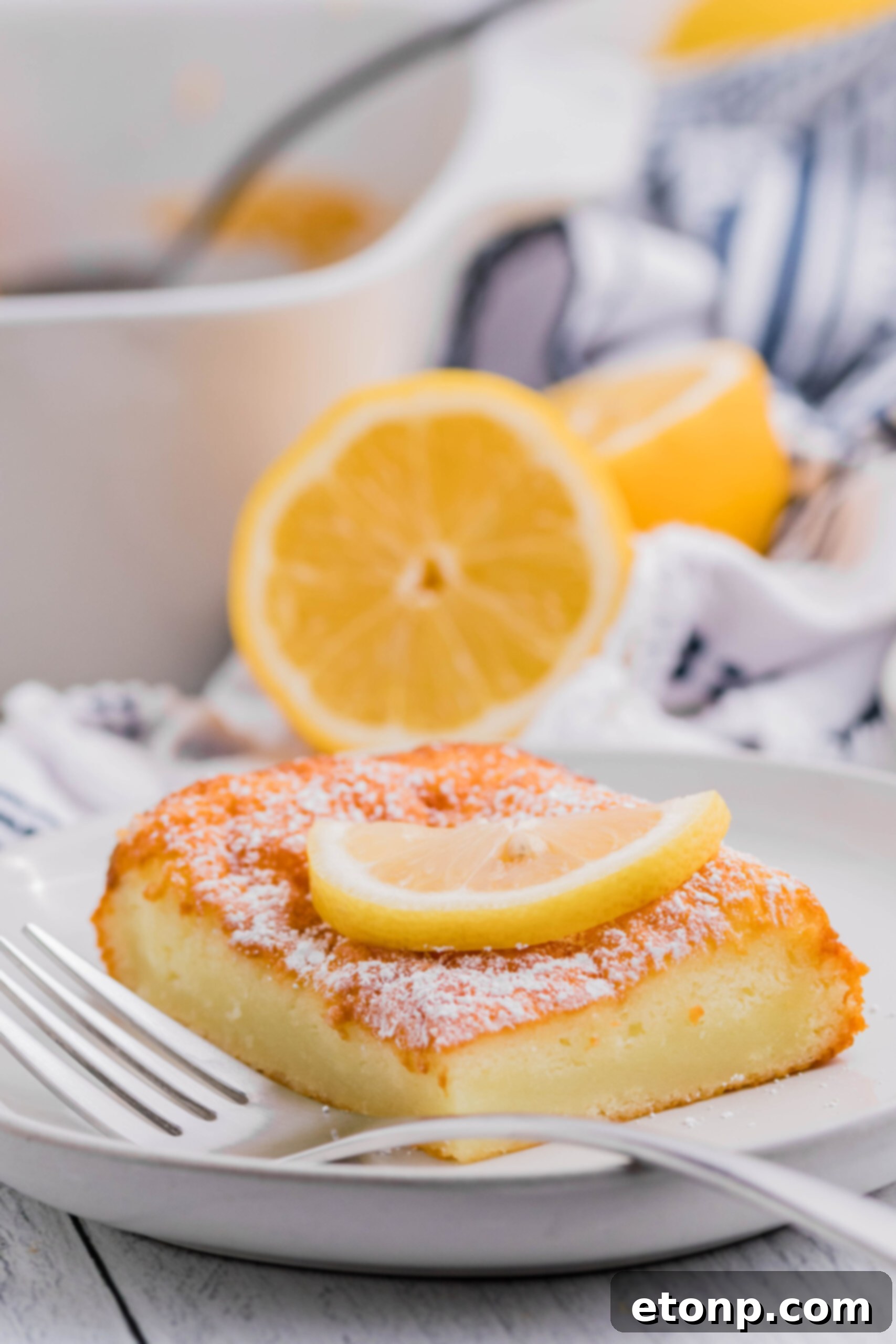 A single slice of 2-Ingredient Lemon Bar on a white plate, elegantly dusted with powdered sugar