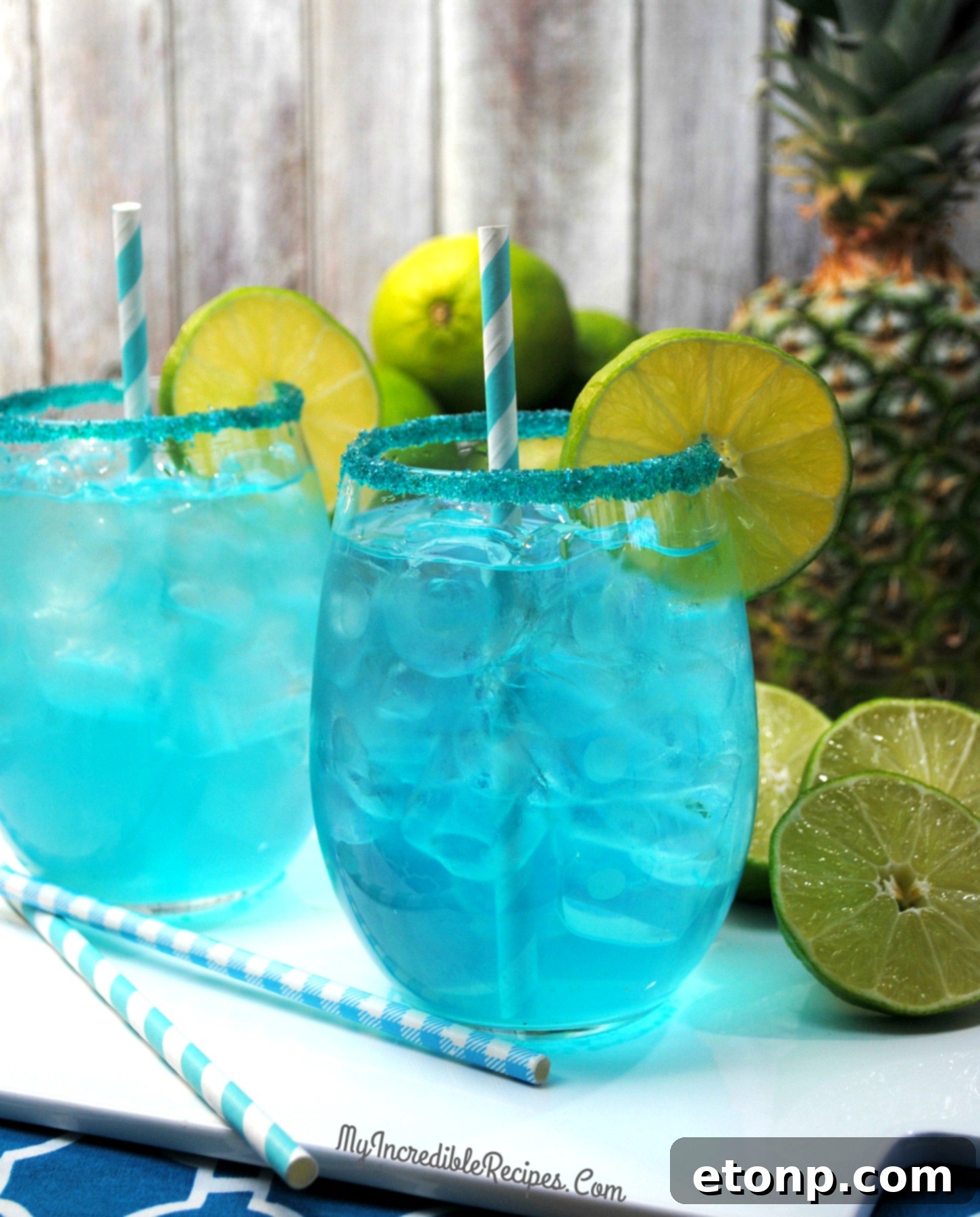 Freshly made Kinky Pineapple Margaritas with ice and blue sugar rims, inviting a refreshing sip.