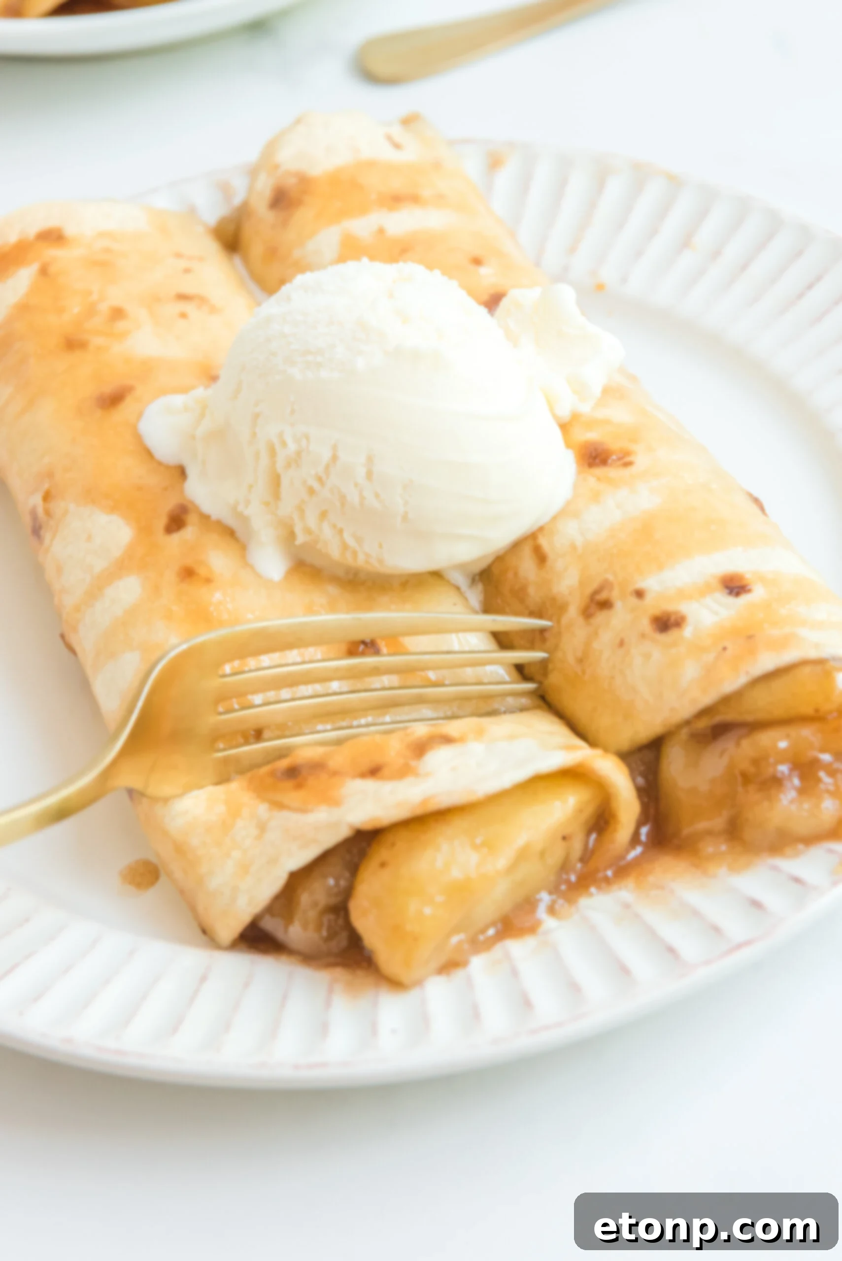 Cinnamon Apple Enchilada Bake 11 Apple Pie Enchiladas topped with vanilla ice cream, with a fork lifting a piece