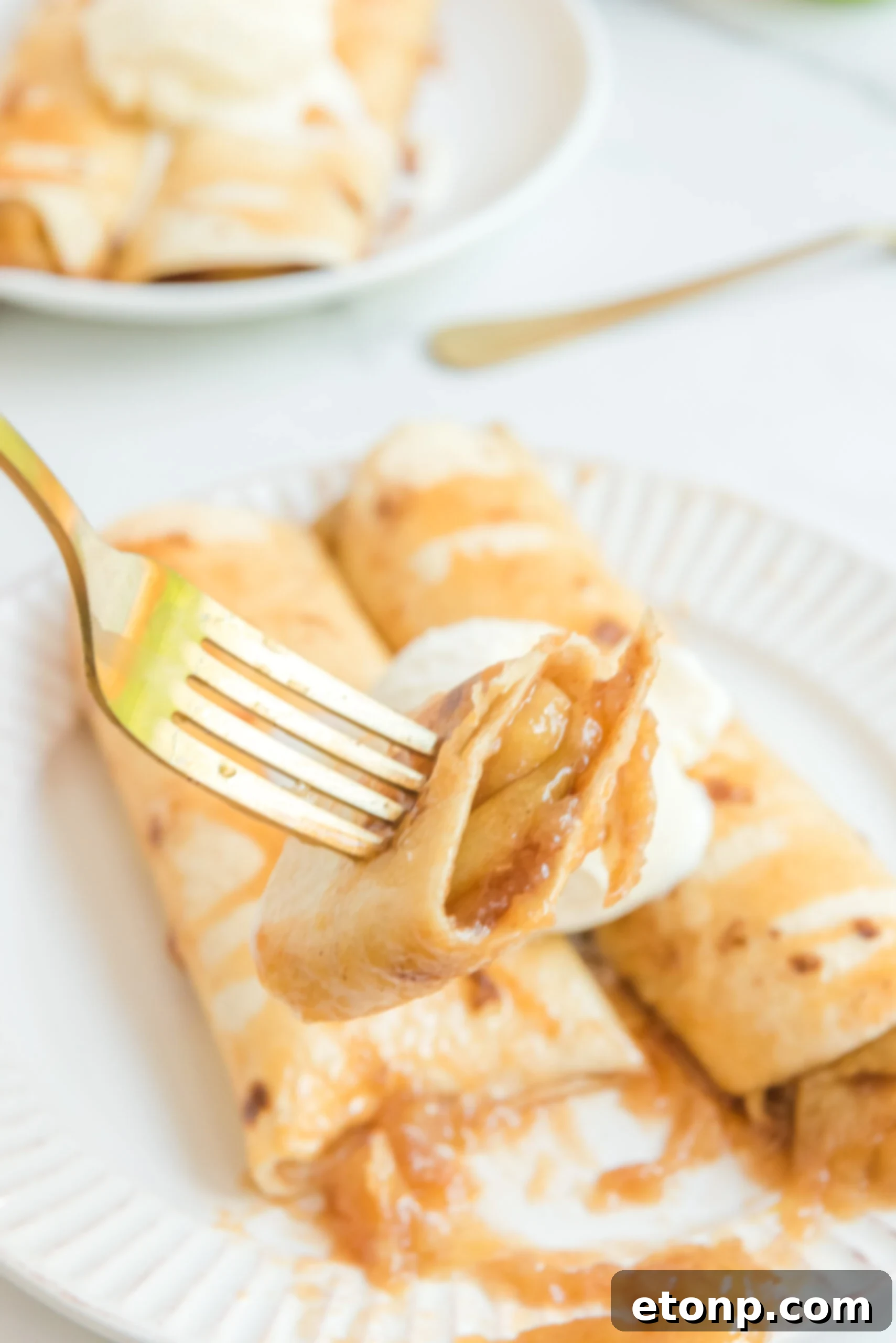 Apple Pie Enchiladas topped with vanilla ice cream with a bite being lifted on a fork
