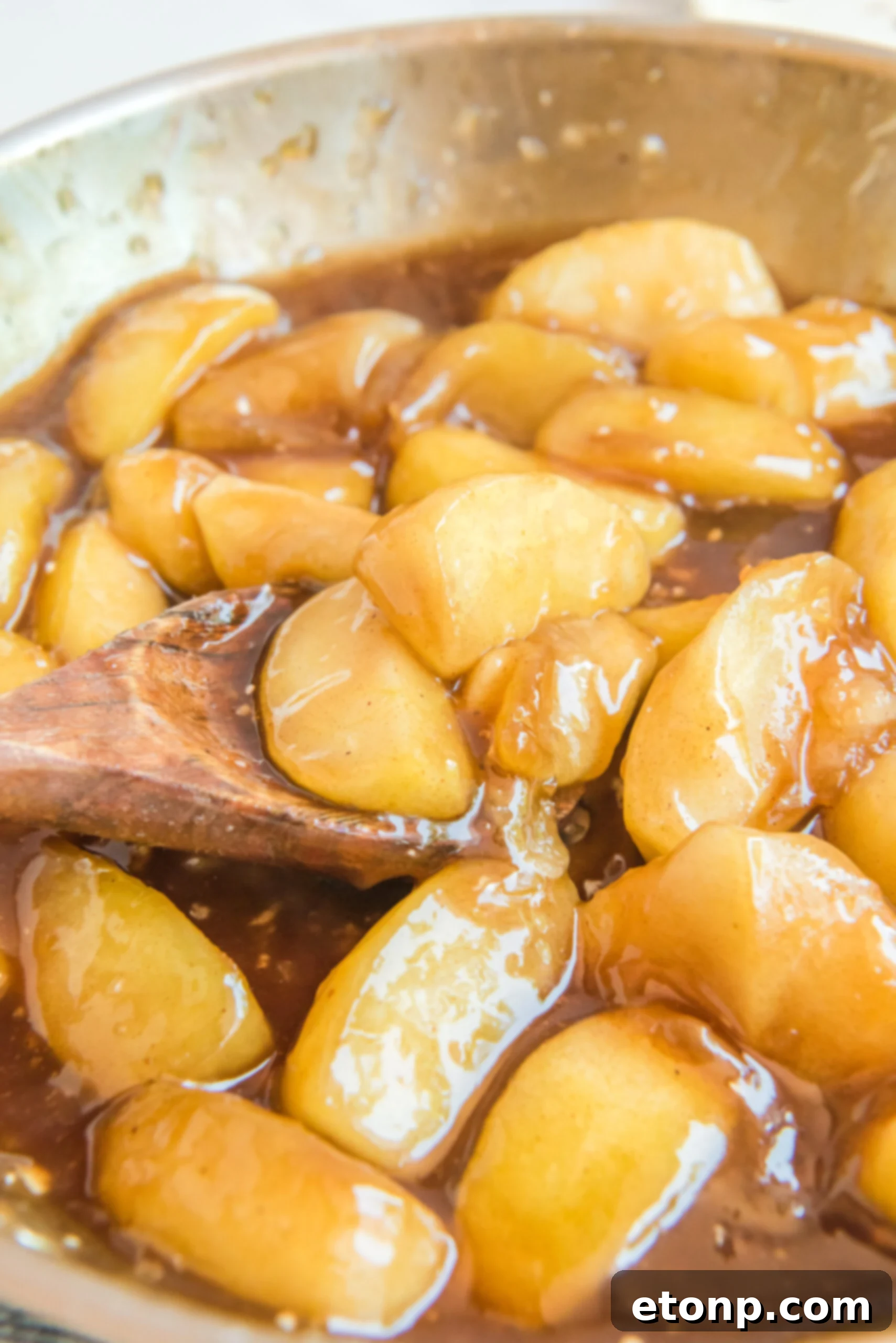 Cinnamon Apple Enchilada Bake 4 Caramelized apple slices cooking in a steel pan on a stovetop