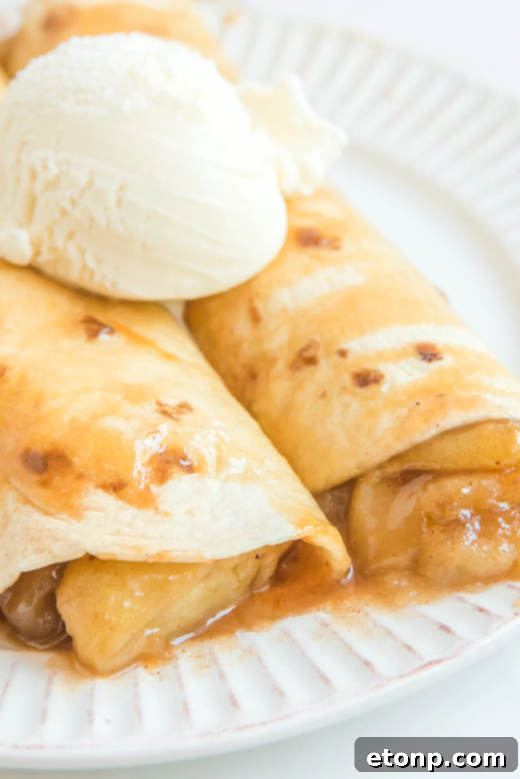 Cinnamon Apple Enchilada Bake 9 Apple Pie Enchiladas topped with vanilla ice cream, showing luscious apple filling