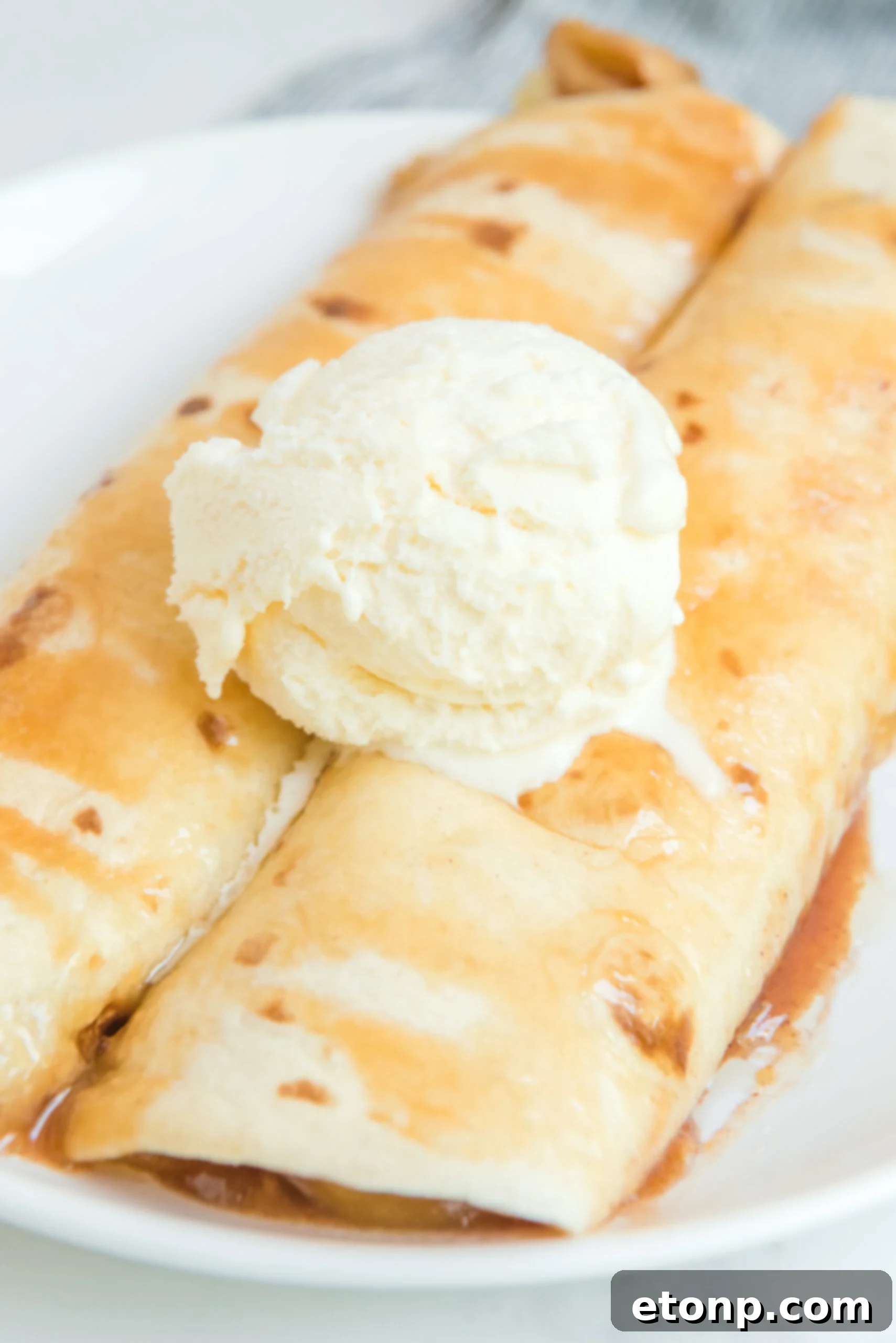 Cinnamon Apple Enchilada Bake 10 Overhead shot of Apple Pie Enchiladas topped with melting vanilla ice cream
