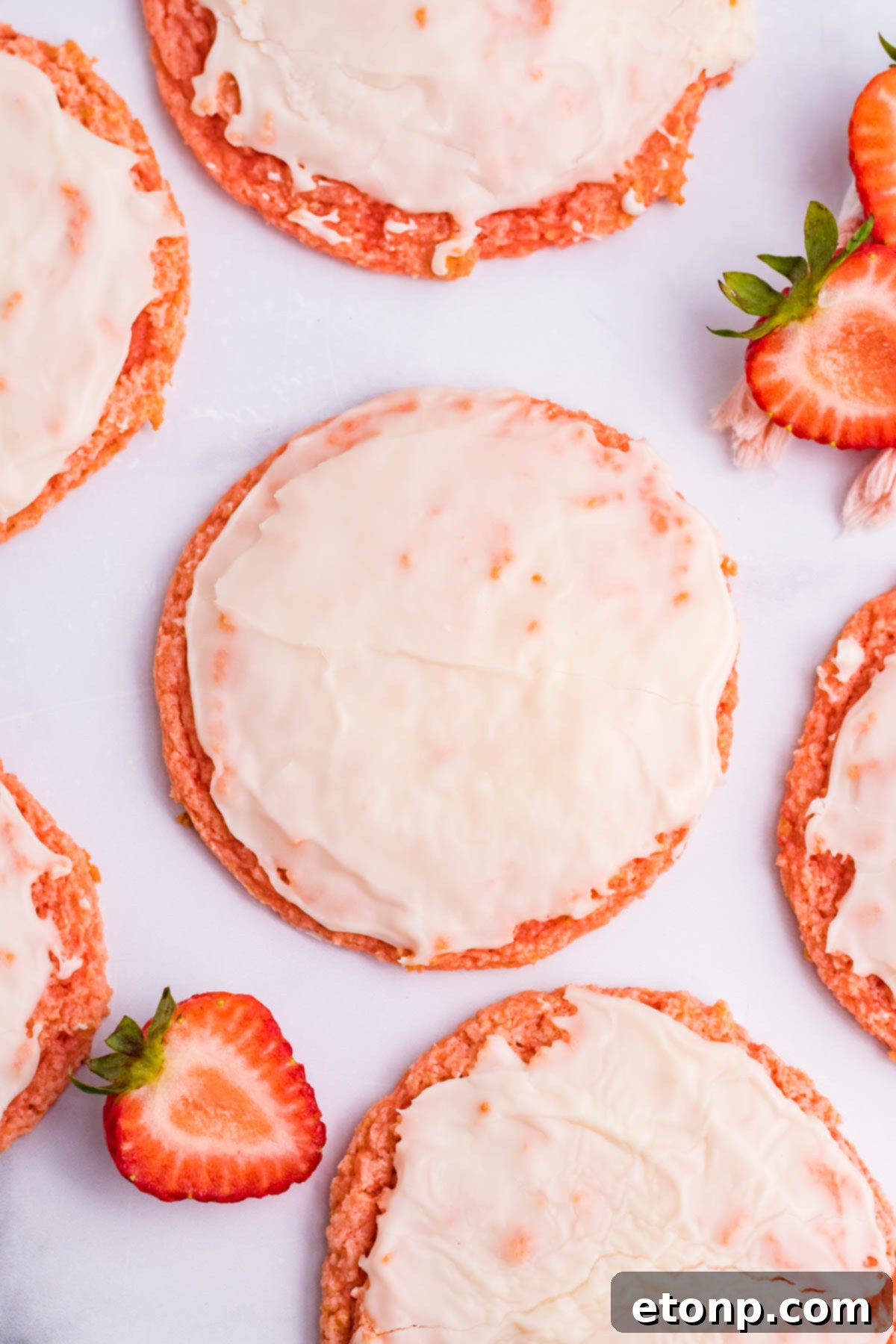 Overhead shot of Strawberry Cool Whip Cookies arranged on a white plate, surrounded by fresh sliced strawberries