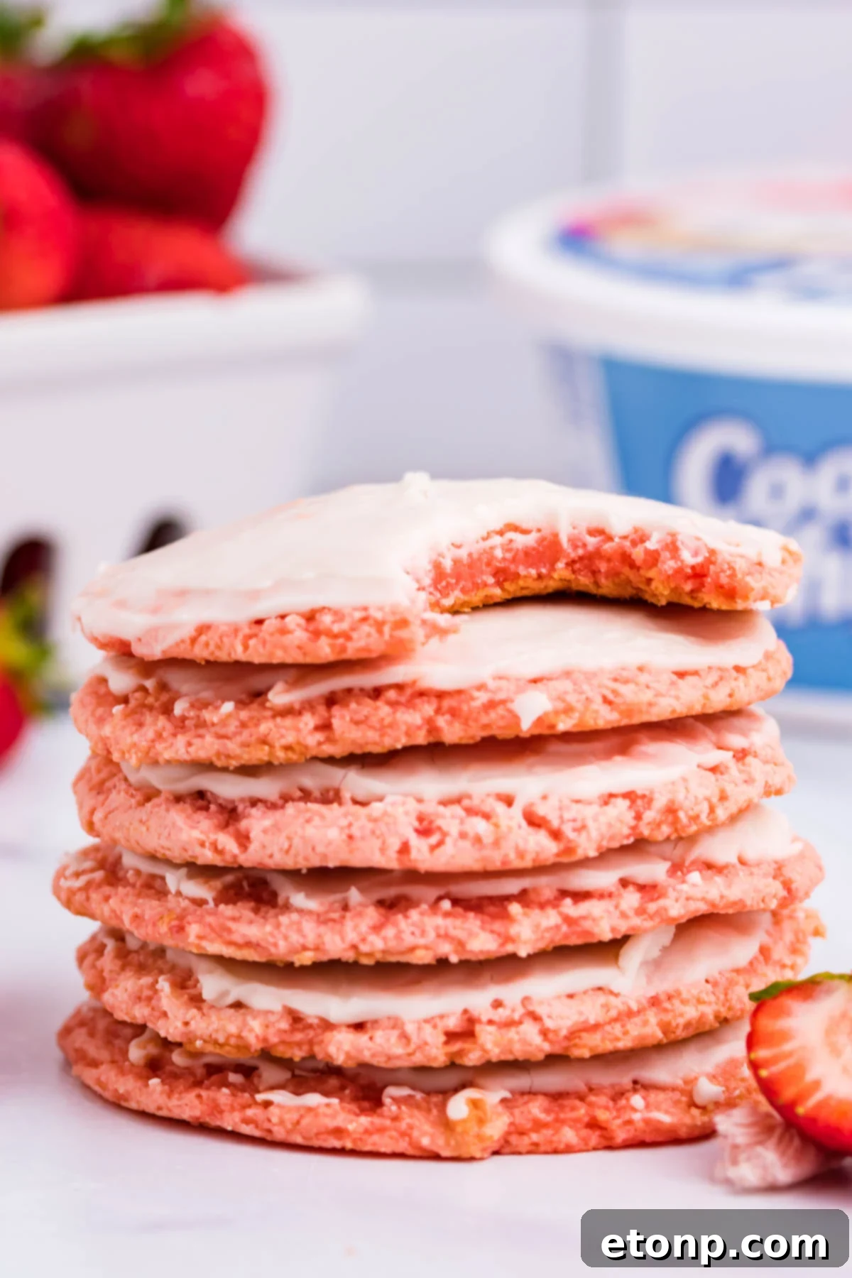 A stack of Strawberry Cool Whip Cookies with the top cookie showing a missing bite, tempting and delicious
