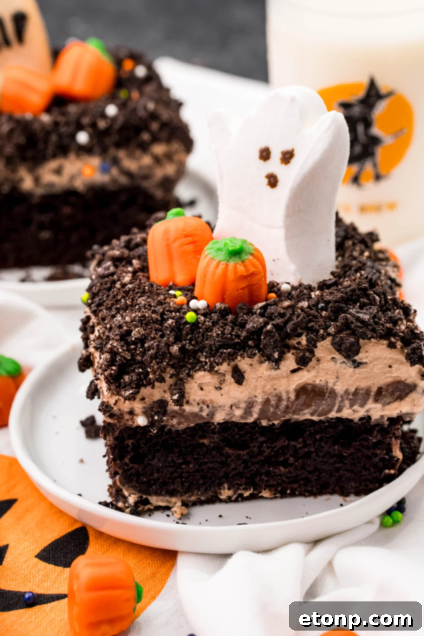 Another mouth-watering shot of a Halloween Dirt Cake slice on a white plate, emphasizing its rich layers and spooky decorations.