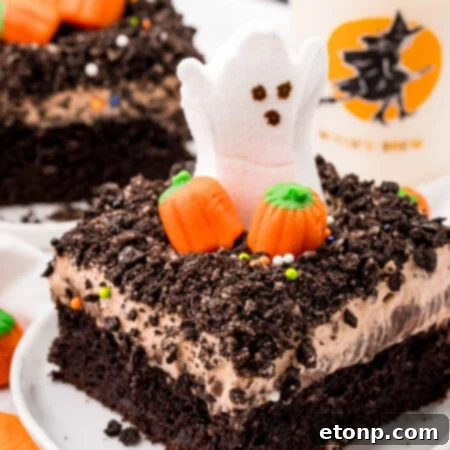 A close-up of a Halloween Dirt Cake, showing the 'dirt' topping, ghost Peeps, and candy pumpkins, ready to be served at a festive gathering.