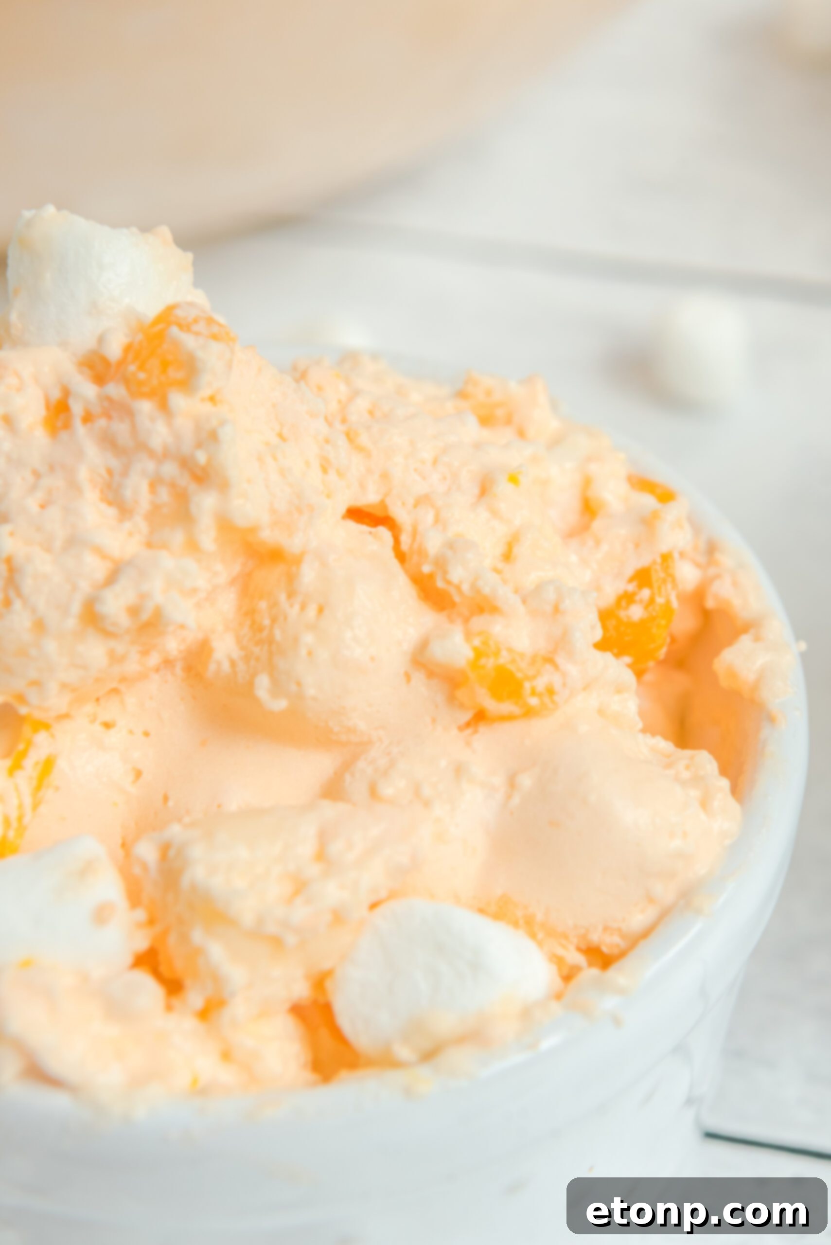 Orange Creamsicle Salad served in a pristine white bowl, showcasing its smooth, creamy texture and vibrant color.