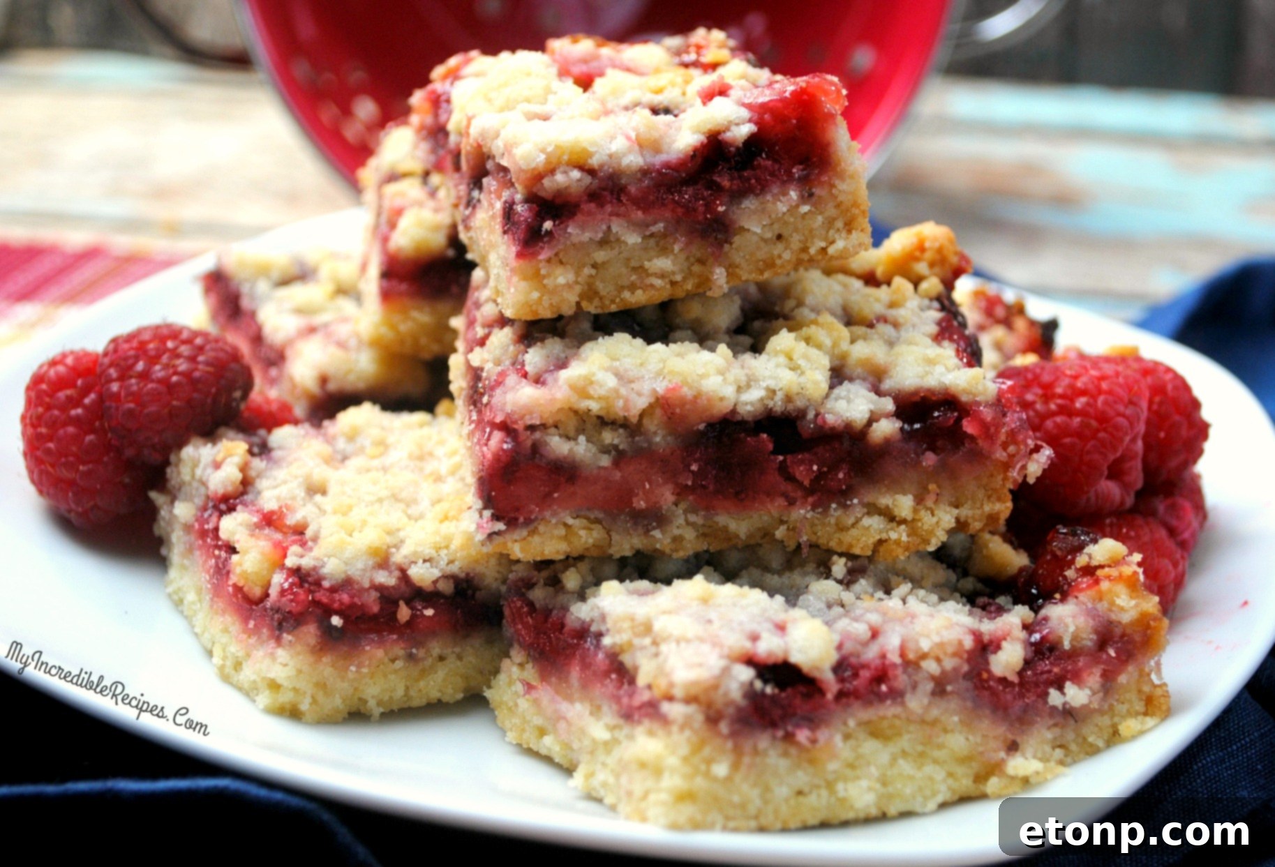 Several Raspberry Crumble Bars displayed on a rustic wooden board, ready to be served.