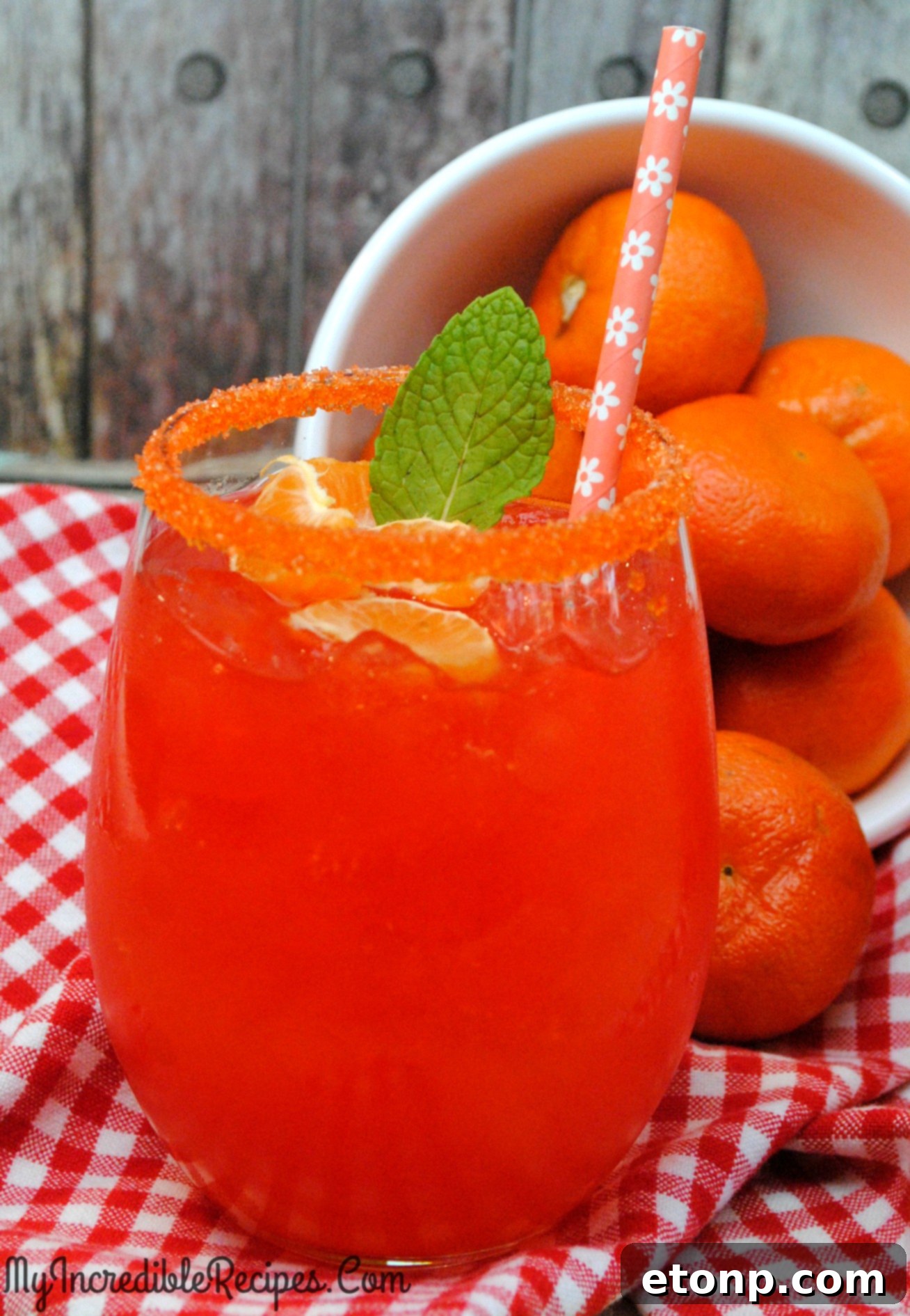 Two vibrant Halo Orange Margaritas garnished with orange slices and mint, reflecting the summer sun.