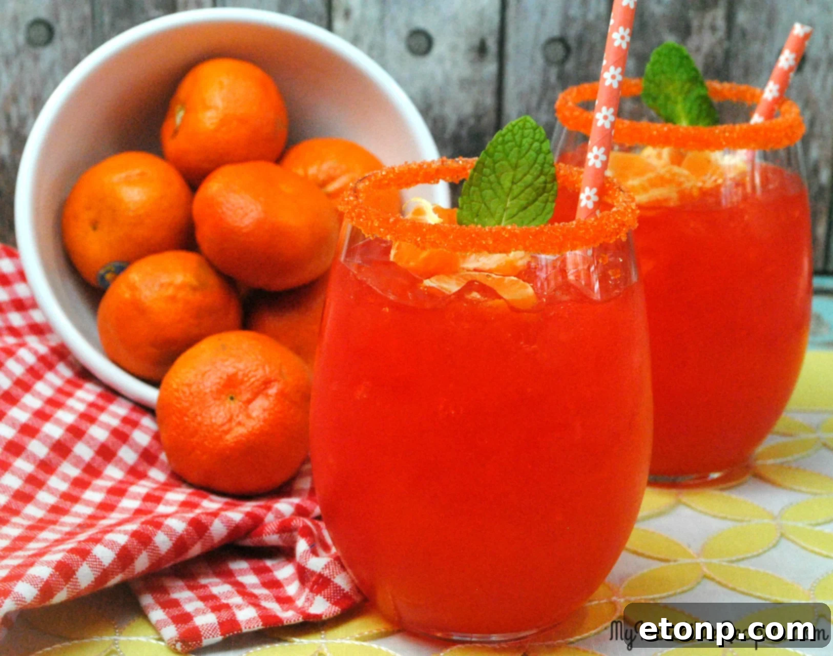 A person holding a glass of Halo Orange Margarita by a poolside, enjoying a relaxing summer day.