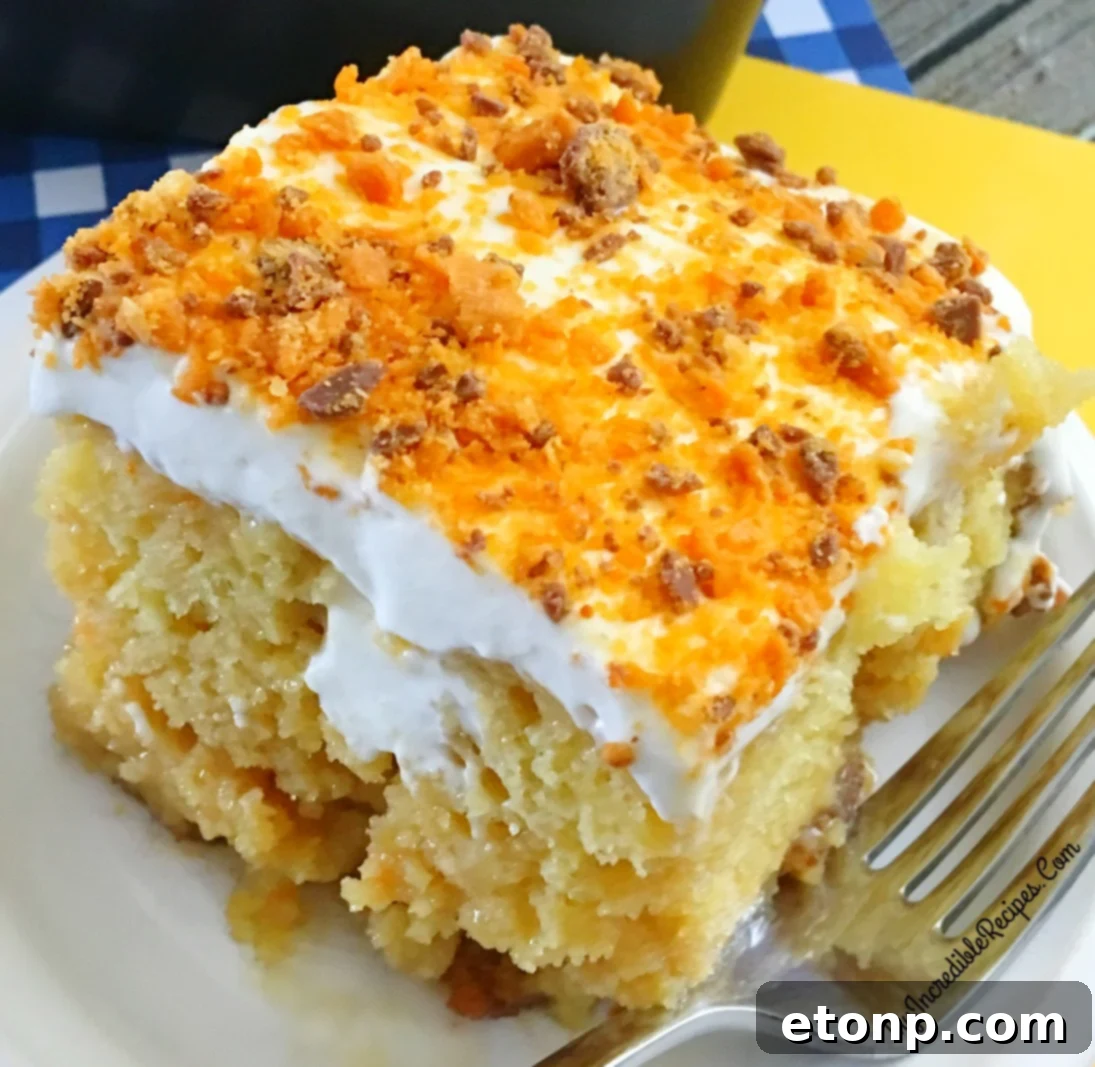 Butterfinger Bliss Cake 2 close-up of delicious Butterfinger Caramel Poke Cake with whipped cream and crushed candy