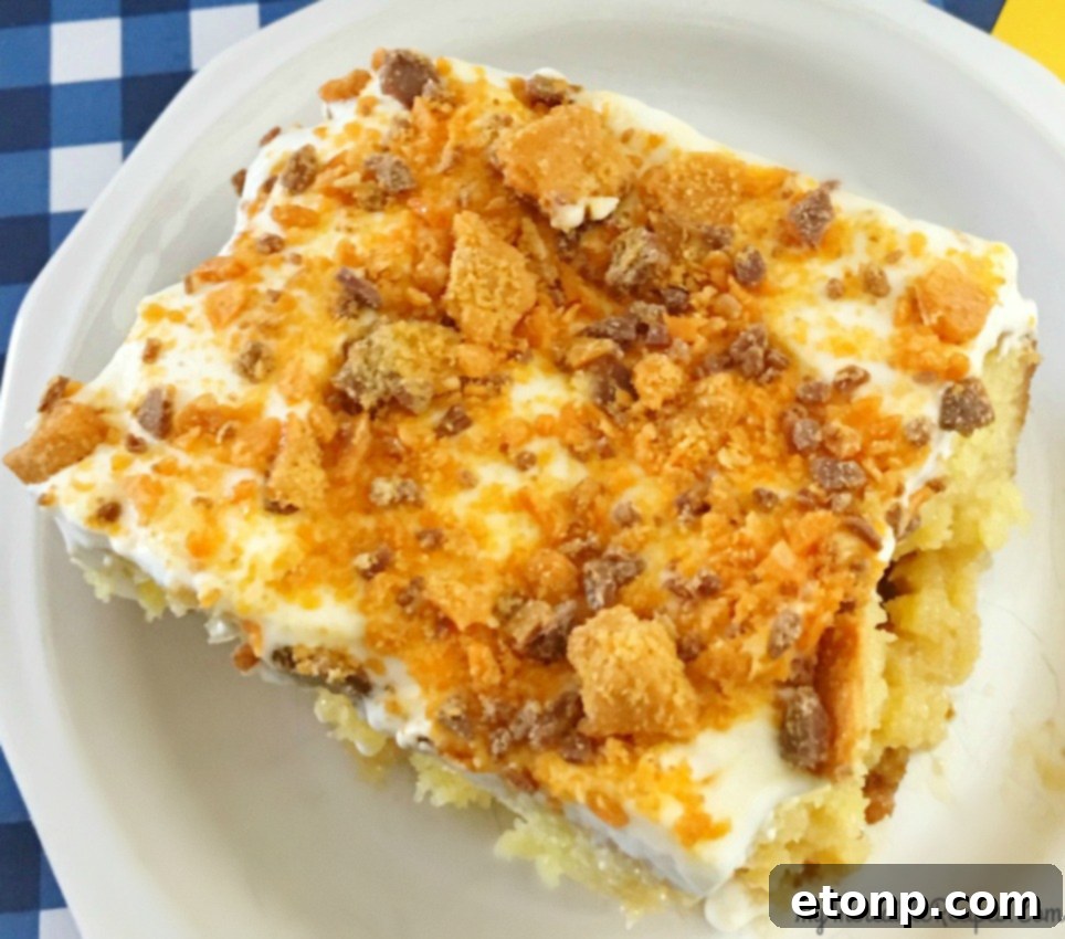 Butterfinger Bliss Cake 14 a large slice of Butterfinger Caramel Poke Cake with a fork