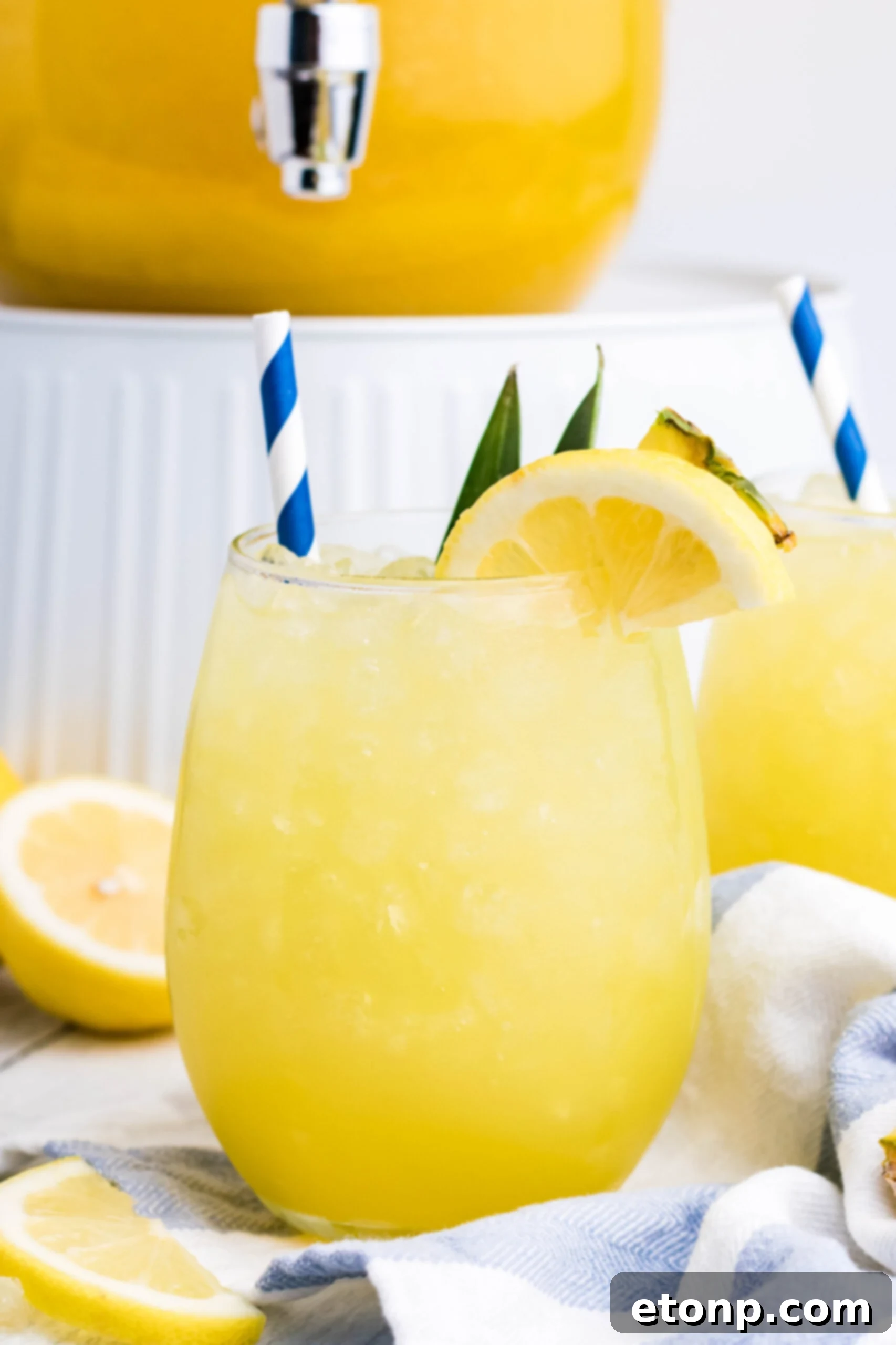 Pineapple Lemonade in a clear glass with ice, garnished with a pineapple wedge and a lemon slice