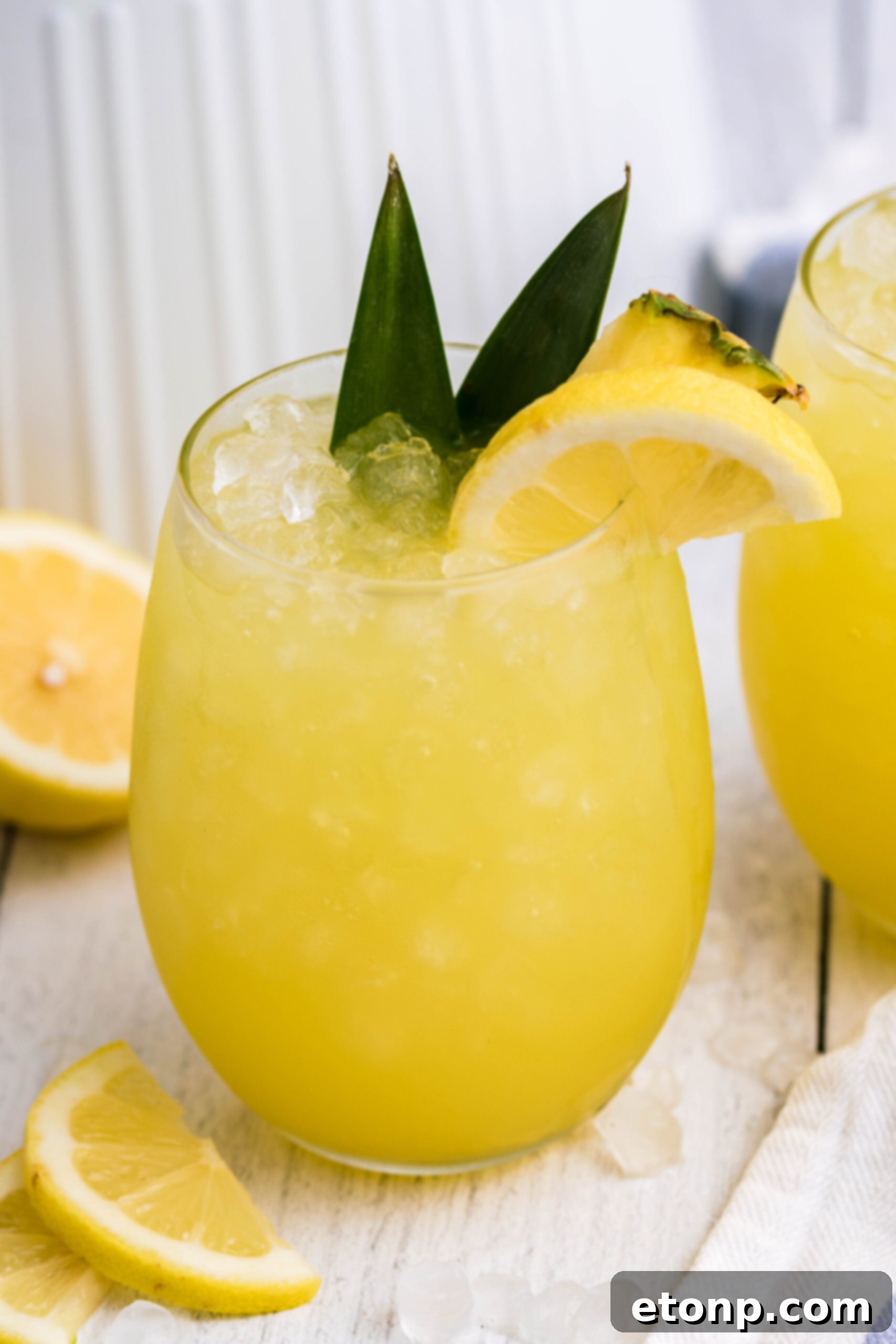 Pineapple Lemonade in a clear glass, garnished with fresh pineapple leaves and a vibrant lemon slice