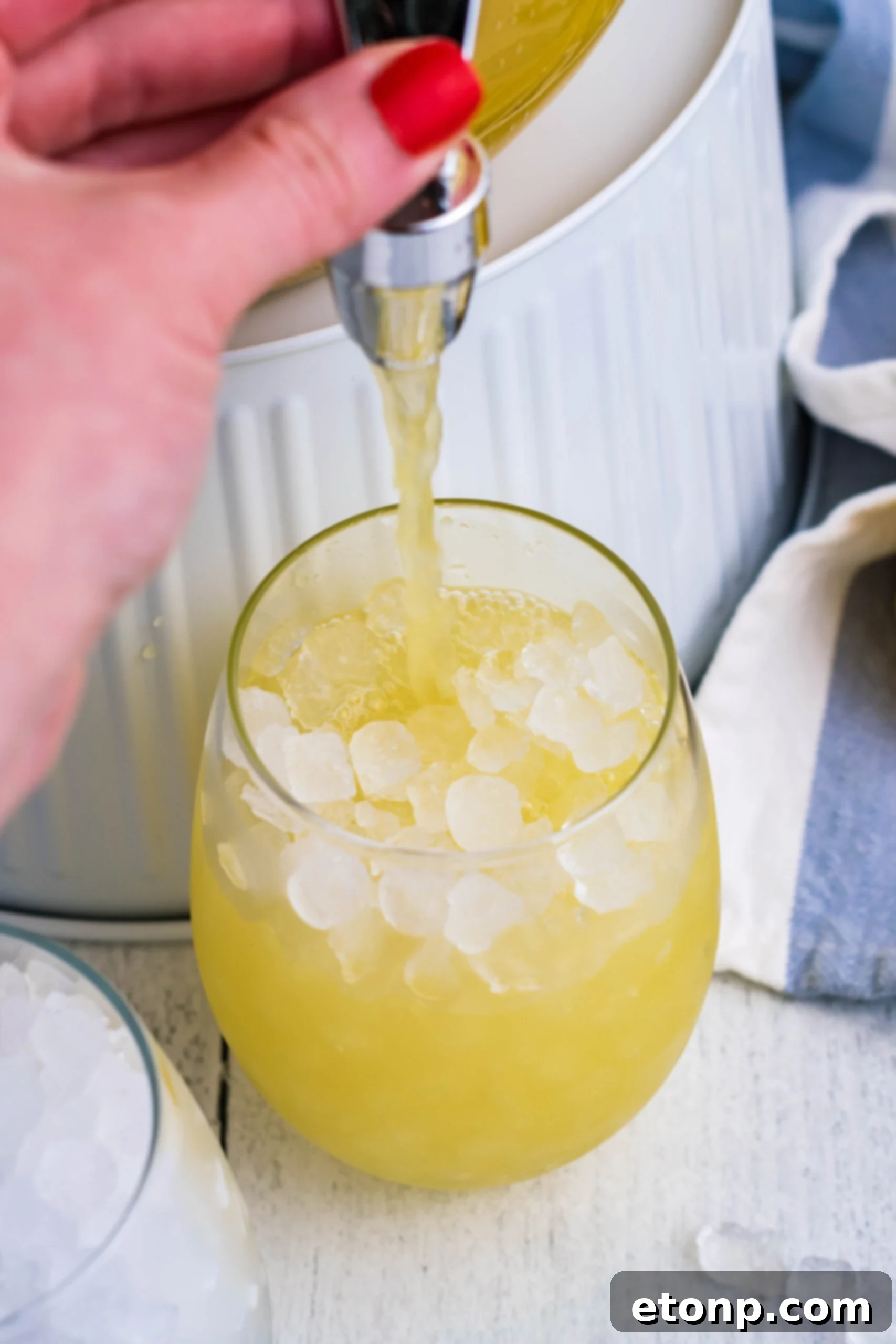 Pineapple Lemonade being poured into a clear glass filled with crushed ice, creating a refreshing splash