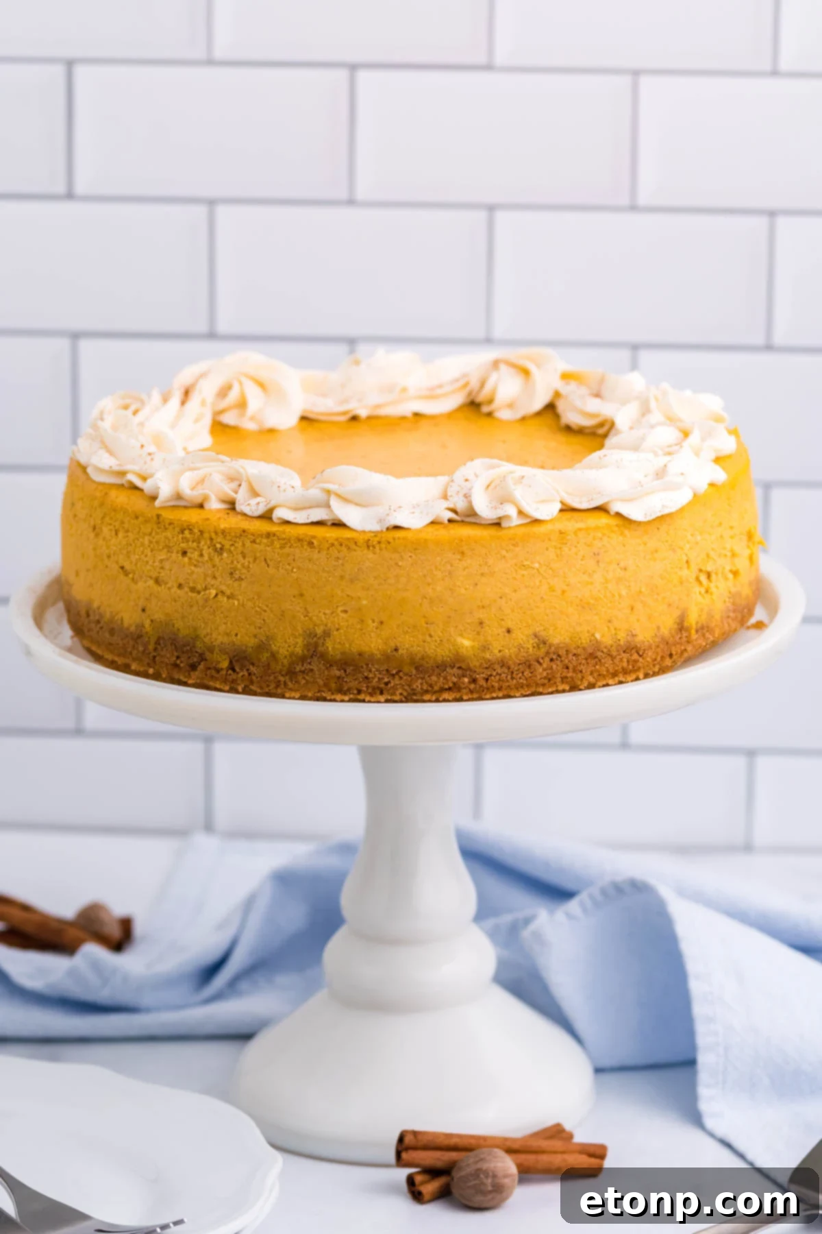 Pumpkin Cheesecake far away shot of it sitting on a white cake stand