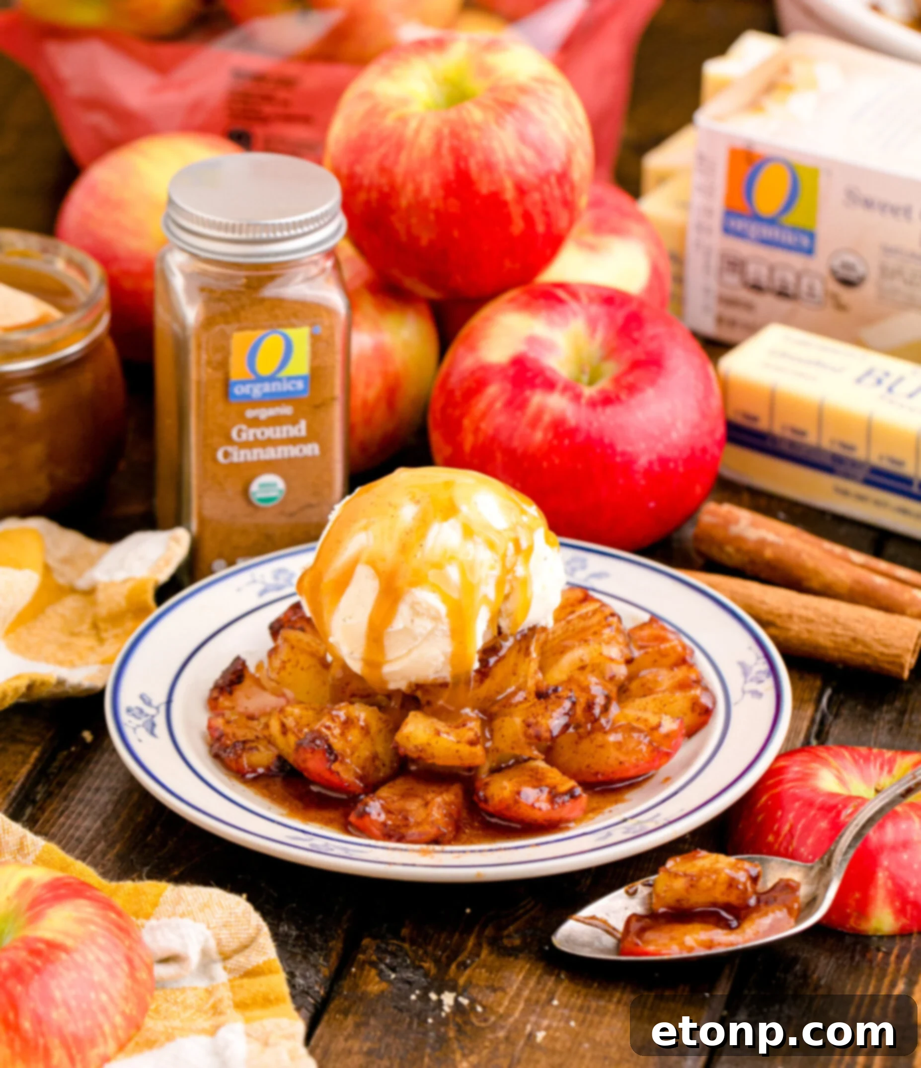 Oven Baked Bloomin Apples on a white plate topped with ice cream on a wood table with apples in the background