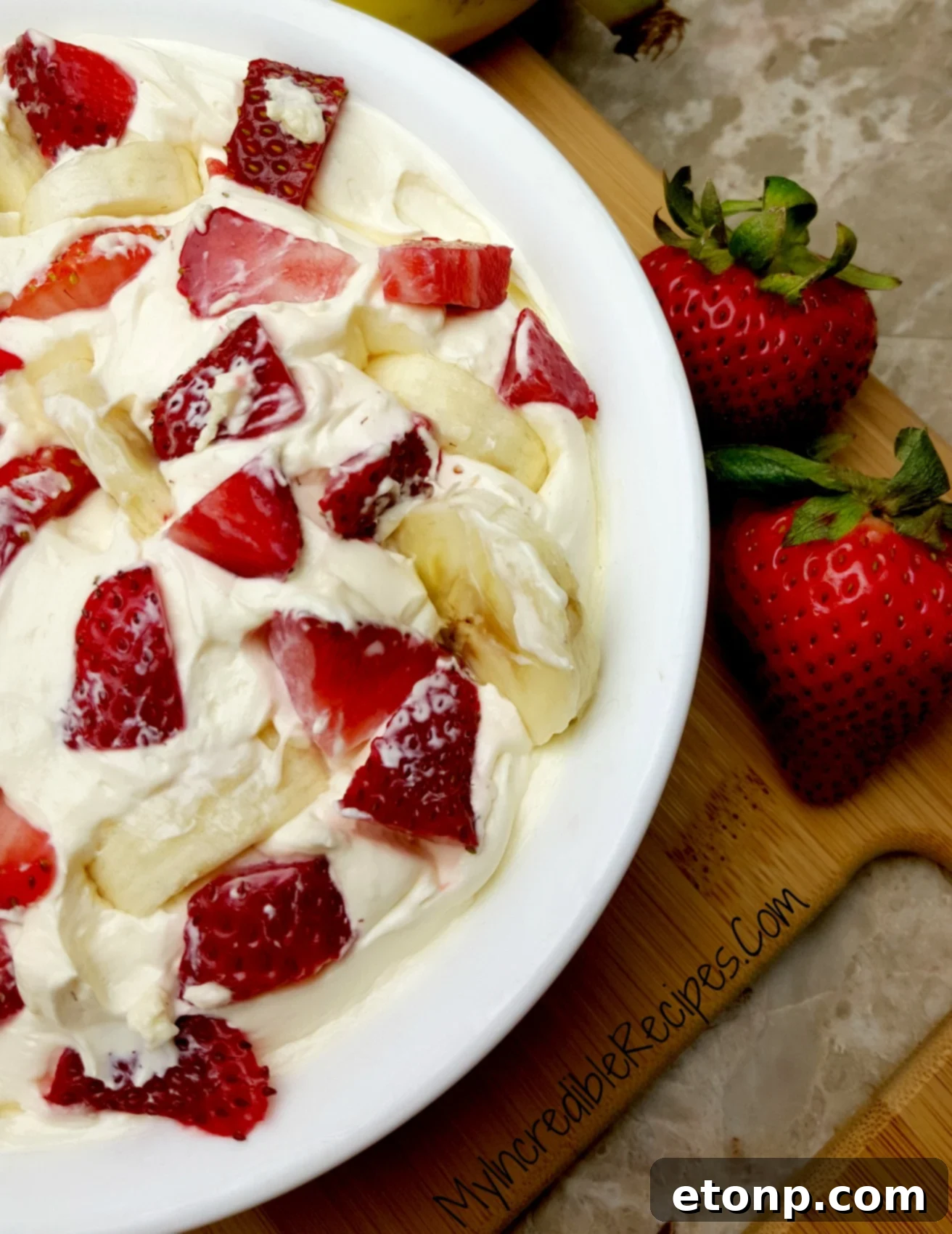 Strawberry Banana Cheesecake Salad Bliss 11 A person's hand reaching for a serving of the cheesecake salad, emphasizing its irresistible appeal.