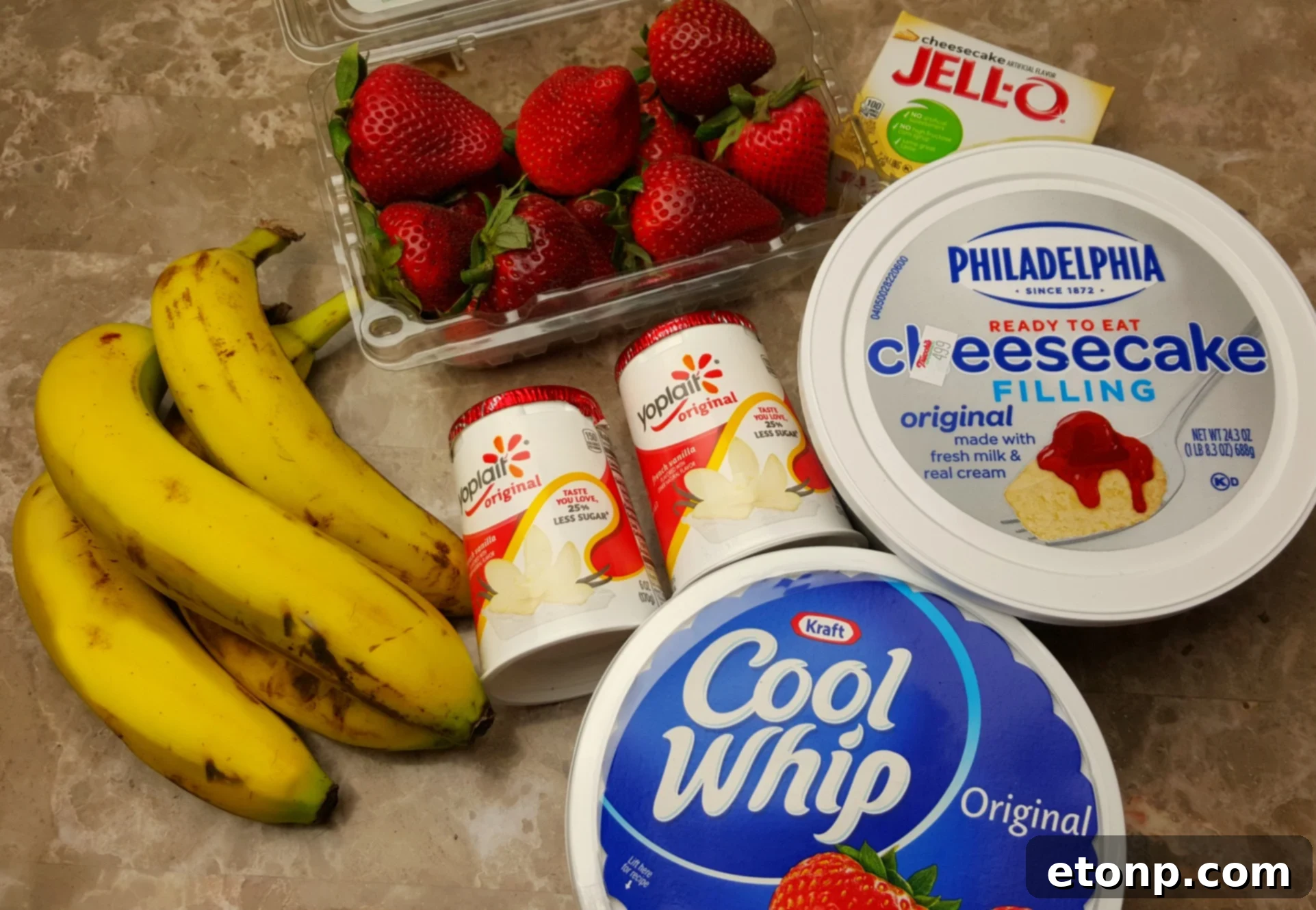 Strawberry Banana Cheesecake Salad Bliss 3 Close-up of fresh ingredients for cheesecake salad, including cream cheese filling, yogurt, cool whip, and pudding mix, ready for preparation.