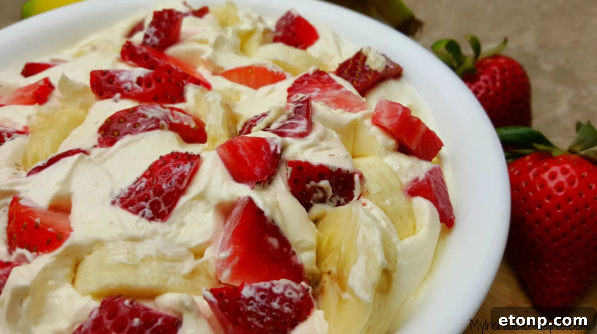 Strawberry Banana Cheesecake Salad Bliss 6 A close-up shot of a spoonful of creamy cheesecake salad with visible pieces of strawberry and banana.