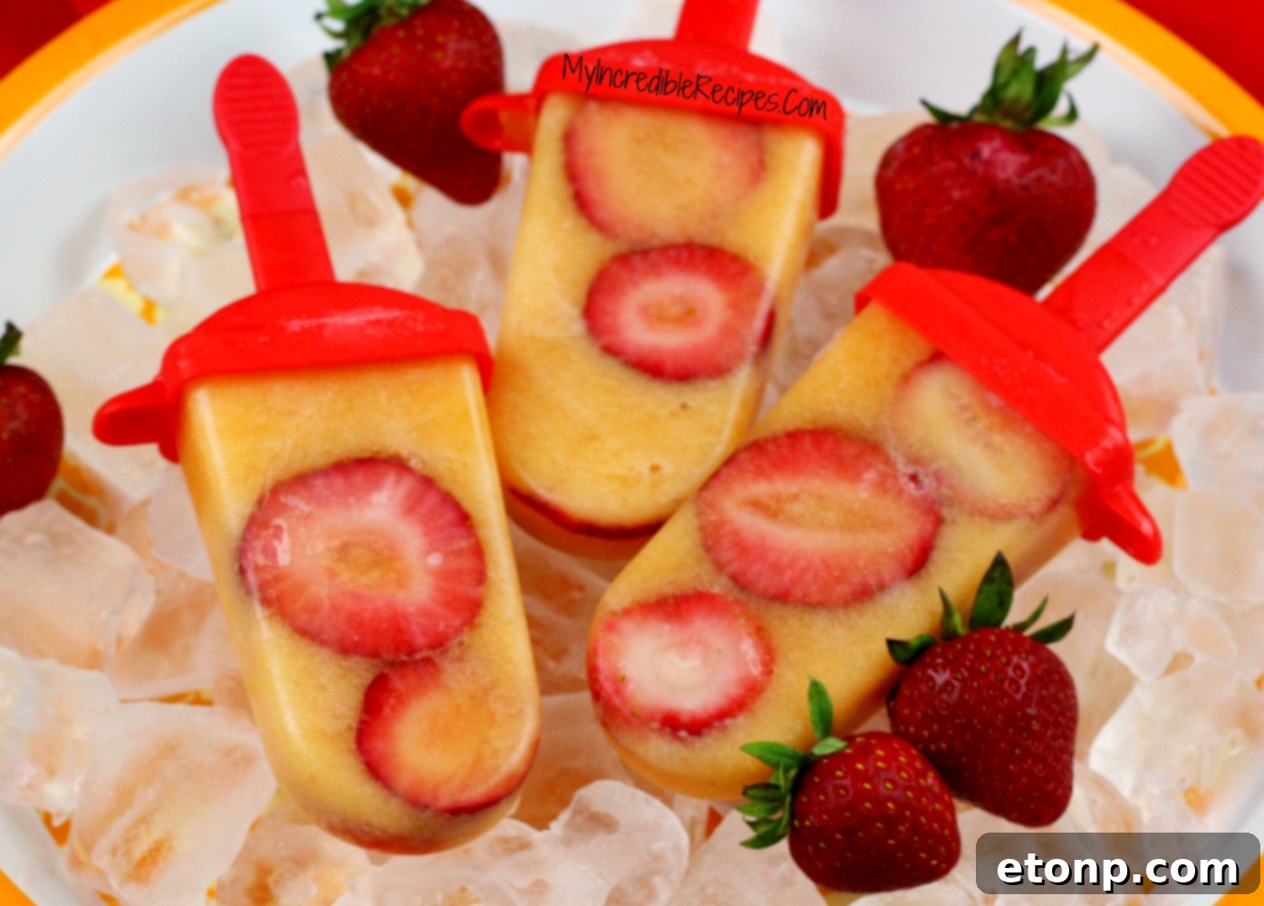 A hand holding a finished Strawberry Cantaloupe popsicle, with other delicious pops in the background