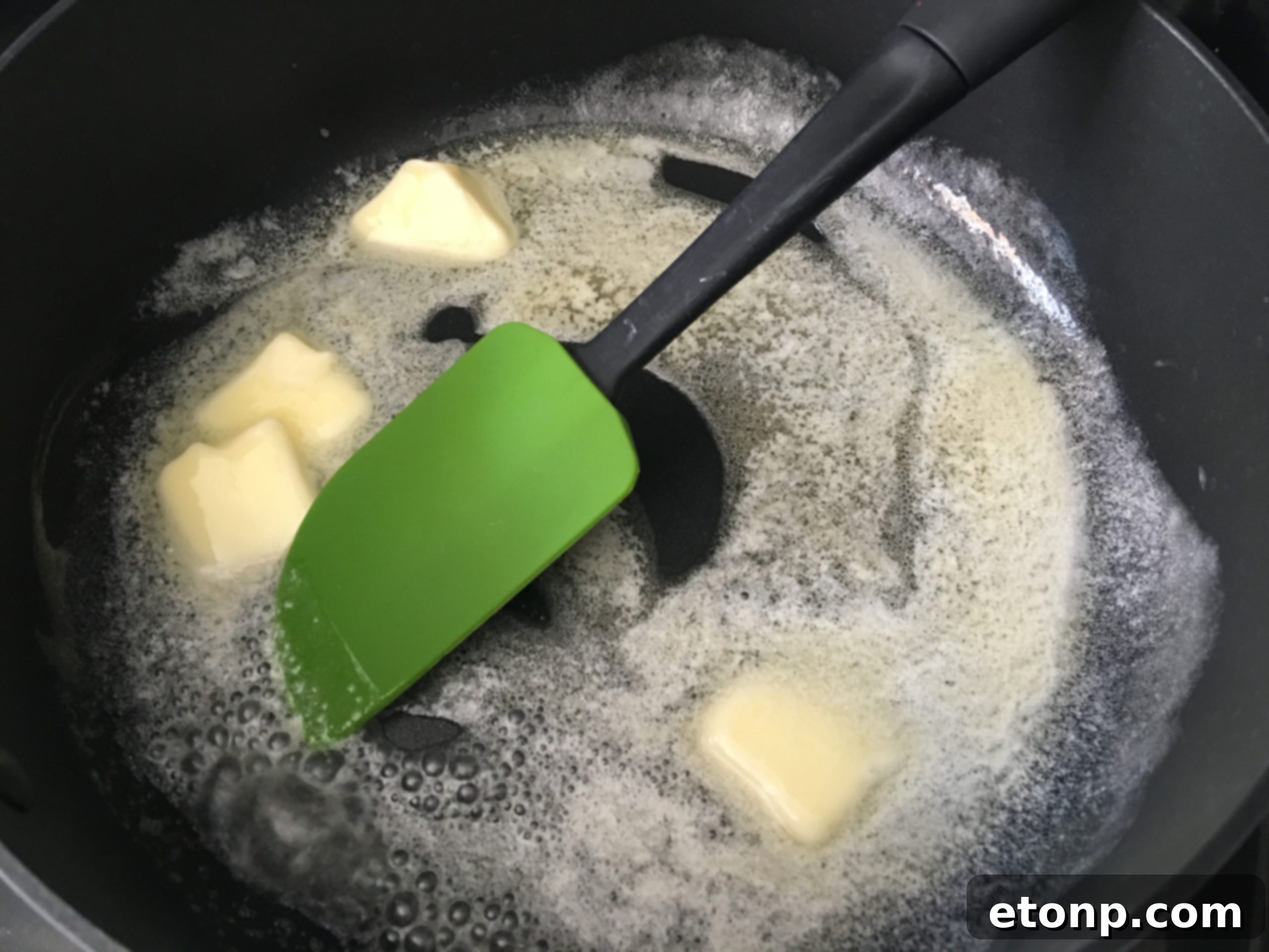 Mixing the butter, cornflakes, and nuts in a large skillet to create the 'fried' topping.