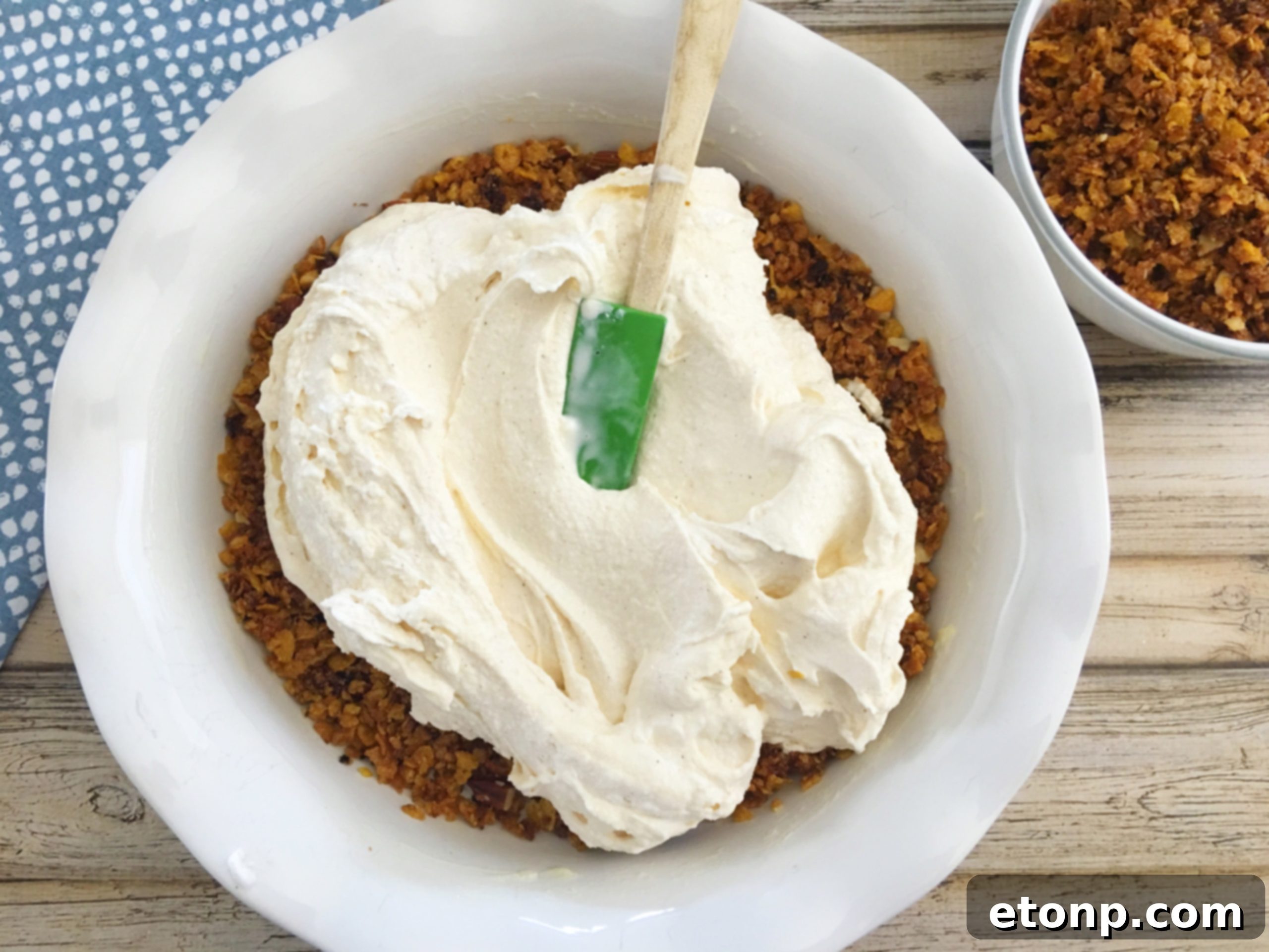 Spreading the creamy ice cream filling evenly over the cornflake crust in a pie dish.