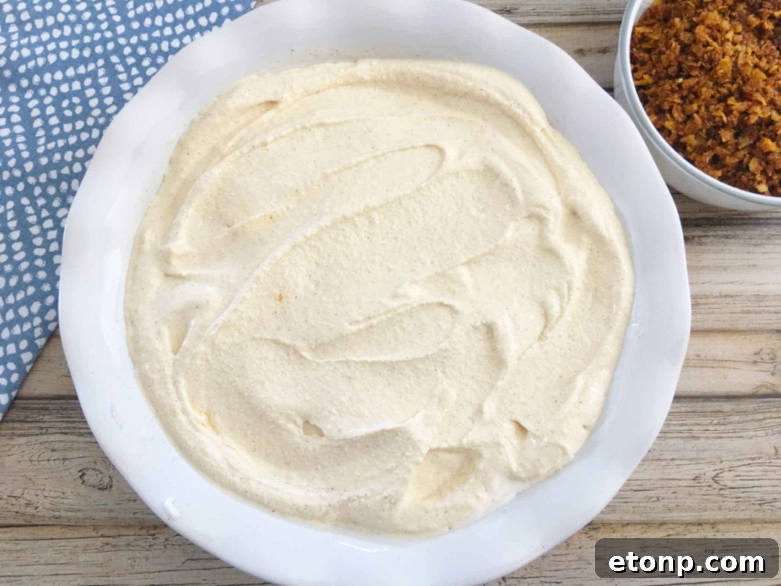 Carefully spreading the smooth ice cream filling in a pie dish, avoiding disturbance to the bottom crust.