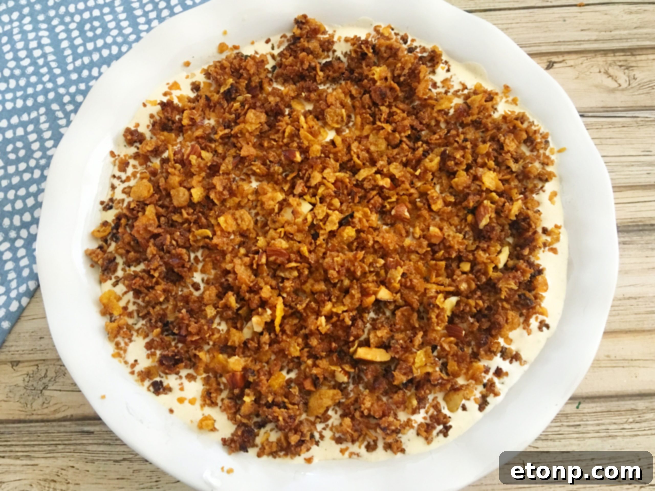 Sprinkling the remaining crispy cornflake mixture over the top of the ice cream pie filling.
