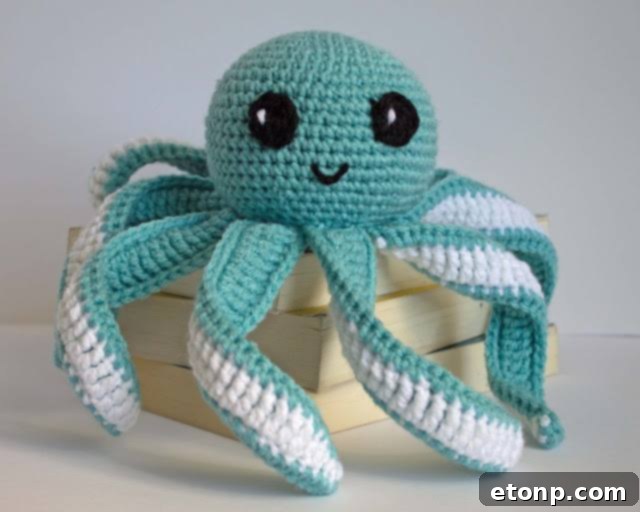 Two colorful crochet octopus baby toys with long, curling tentacles, on a patterned blanket.