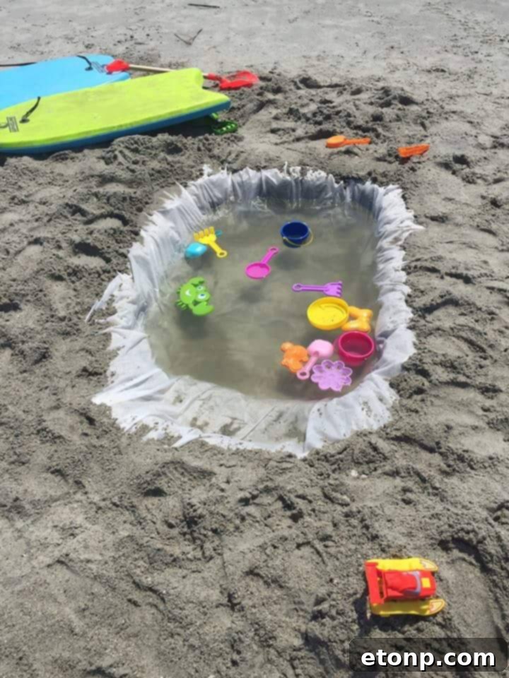 Children playing in a makeshift beach pool created using a blue shower curtain liner on the sand.