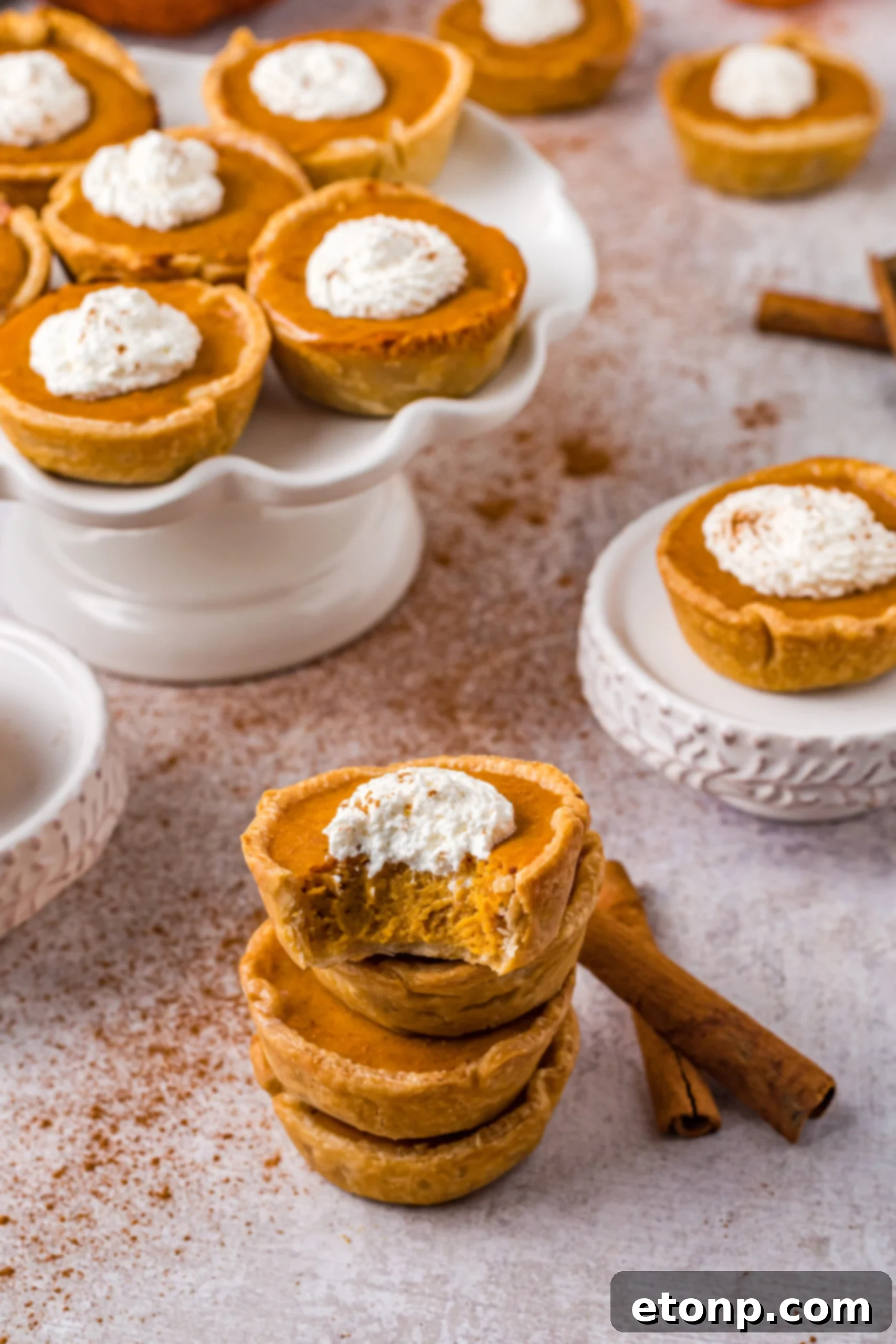Mini Pumpkin Pies stacked with a bite missing and topped with whipped cream 