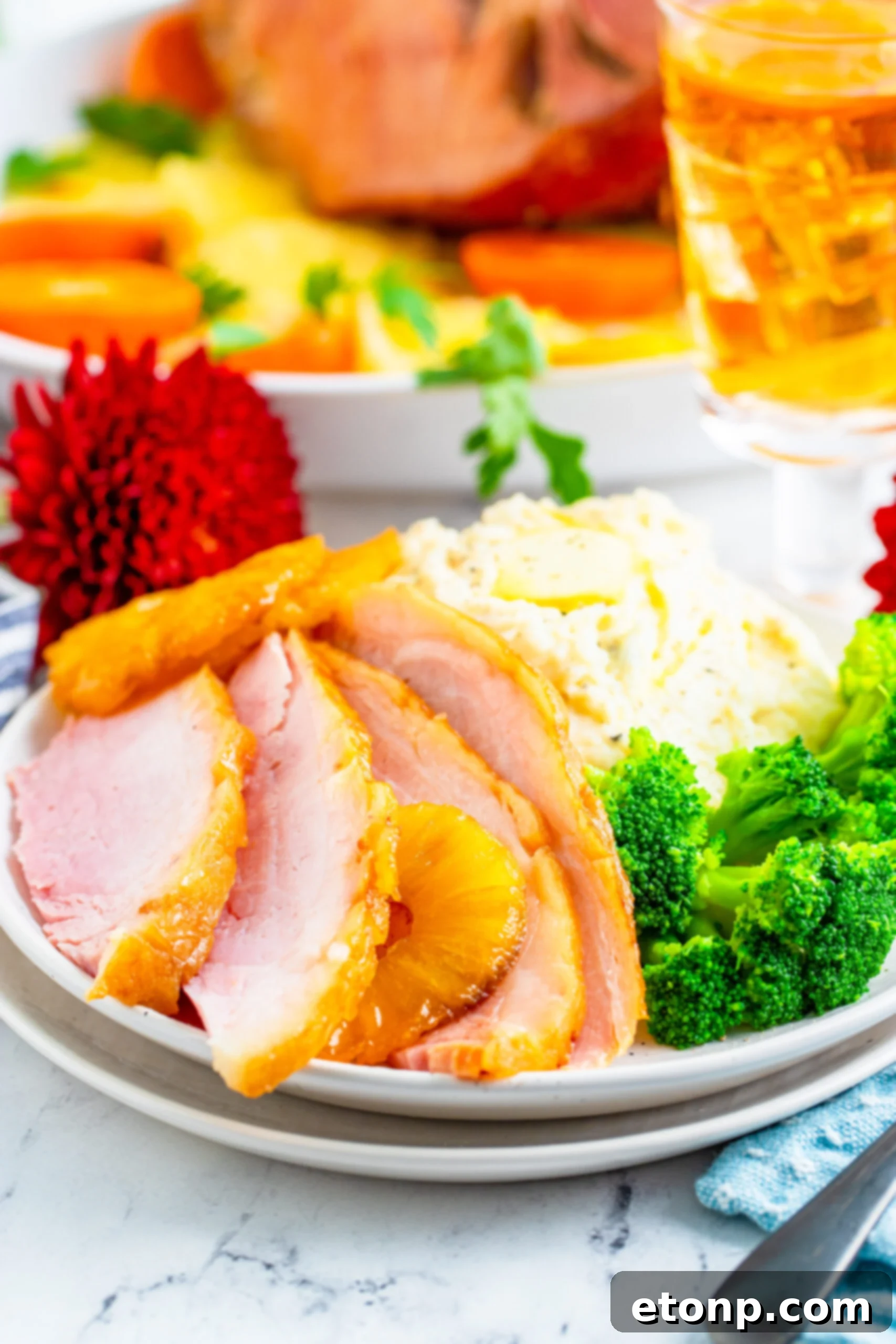 Slices of baked ham plated with broccoli and mashed potatoes. 