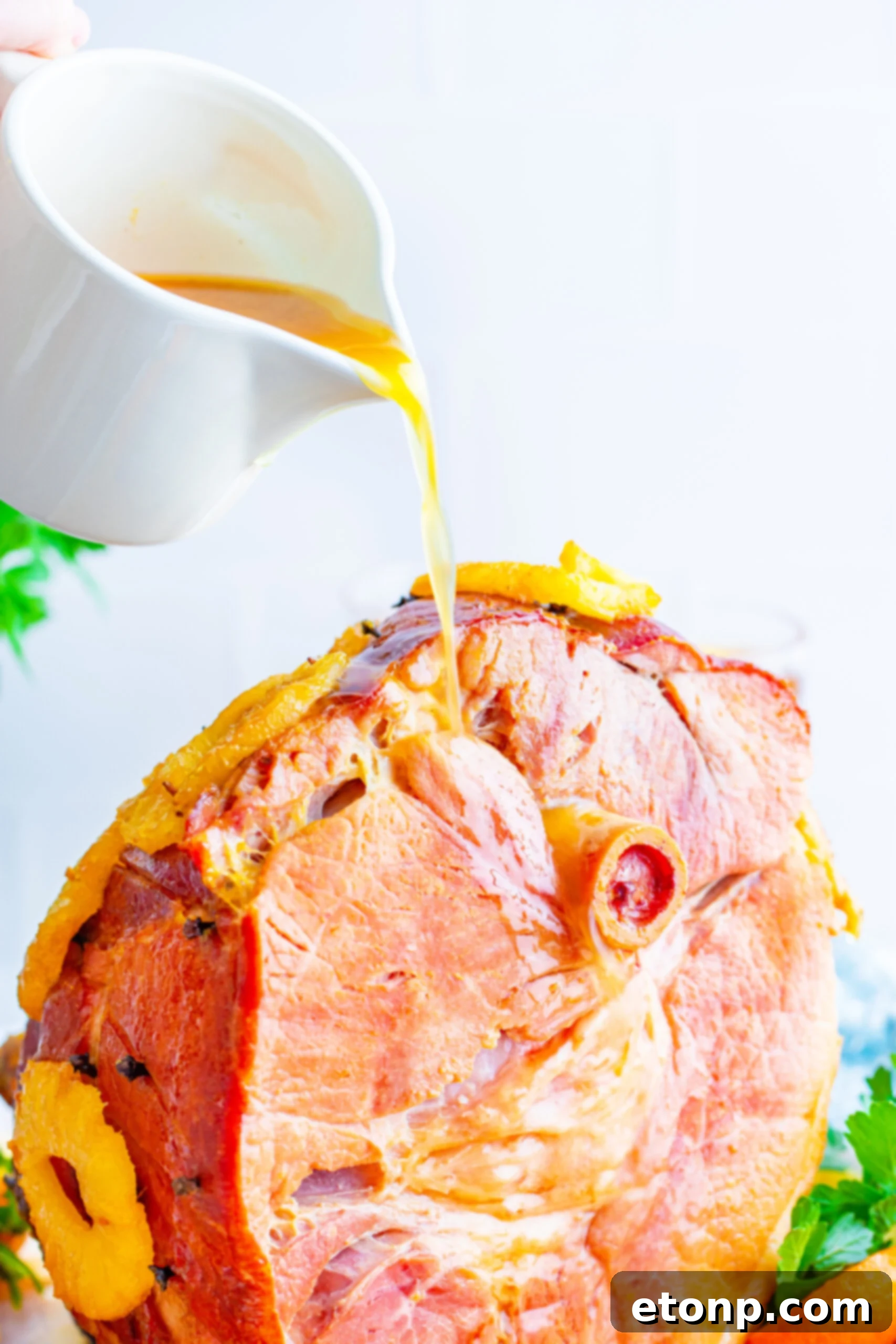 Pouring gravy over top of the finished baked ham. 