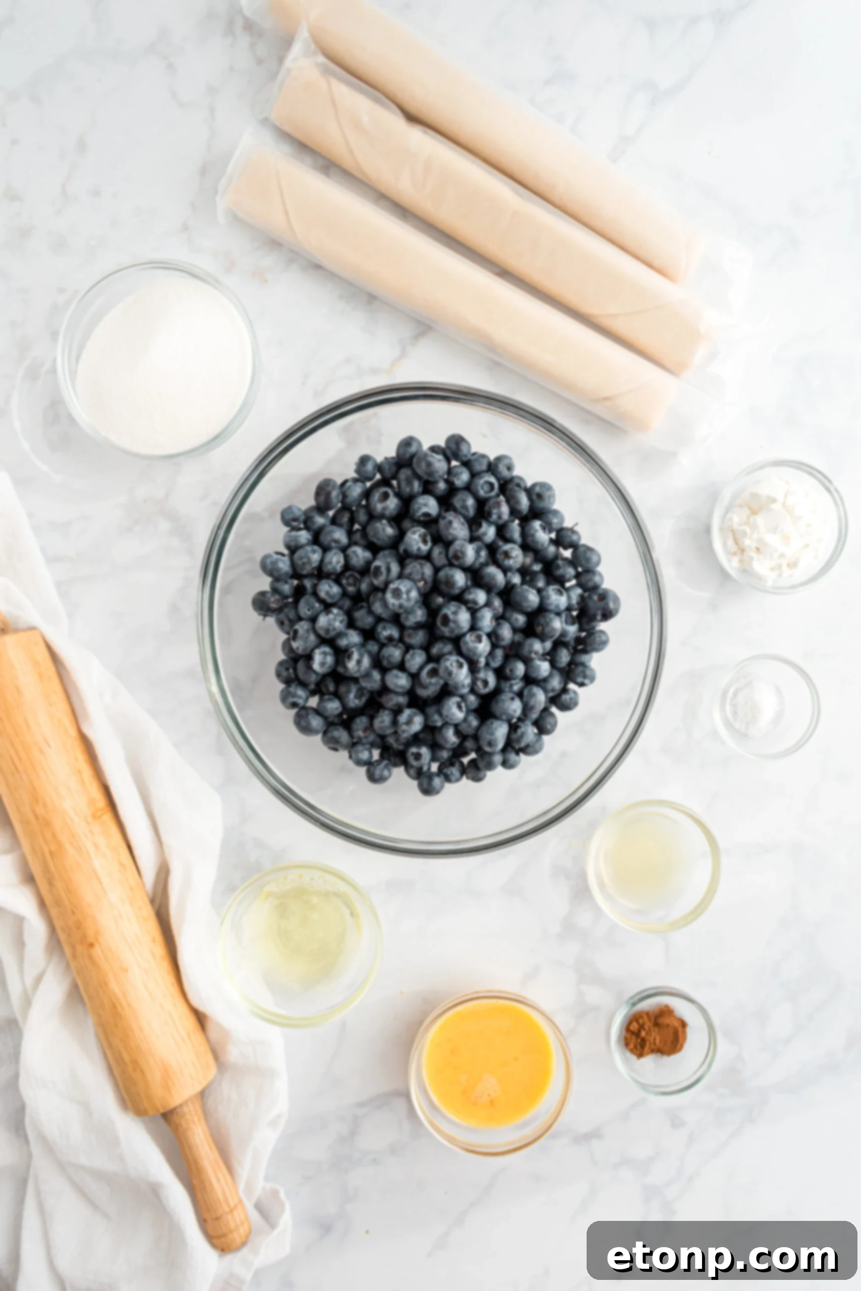 All the fresh ingredients meticulously laid out for the Blueberry Slab Pie recipe, including vibrant blueberries, ready-to-use pie crusts, sugar, and various spices.