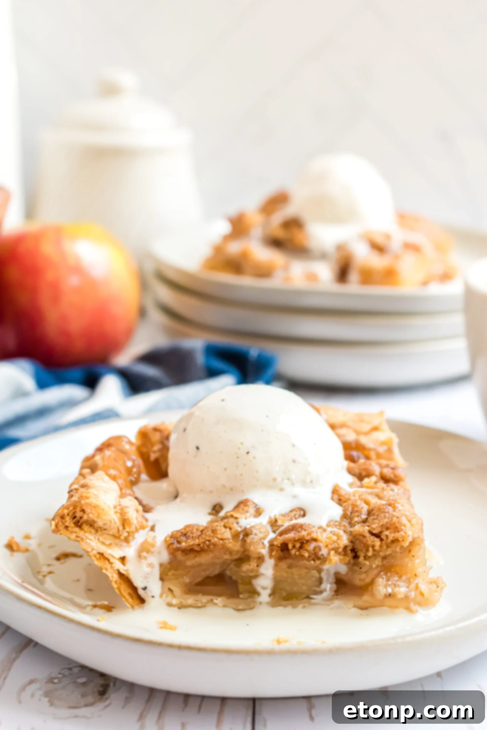Two pieces of apple pie on a white plate with vanilla ice cream. 