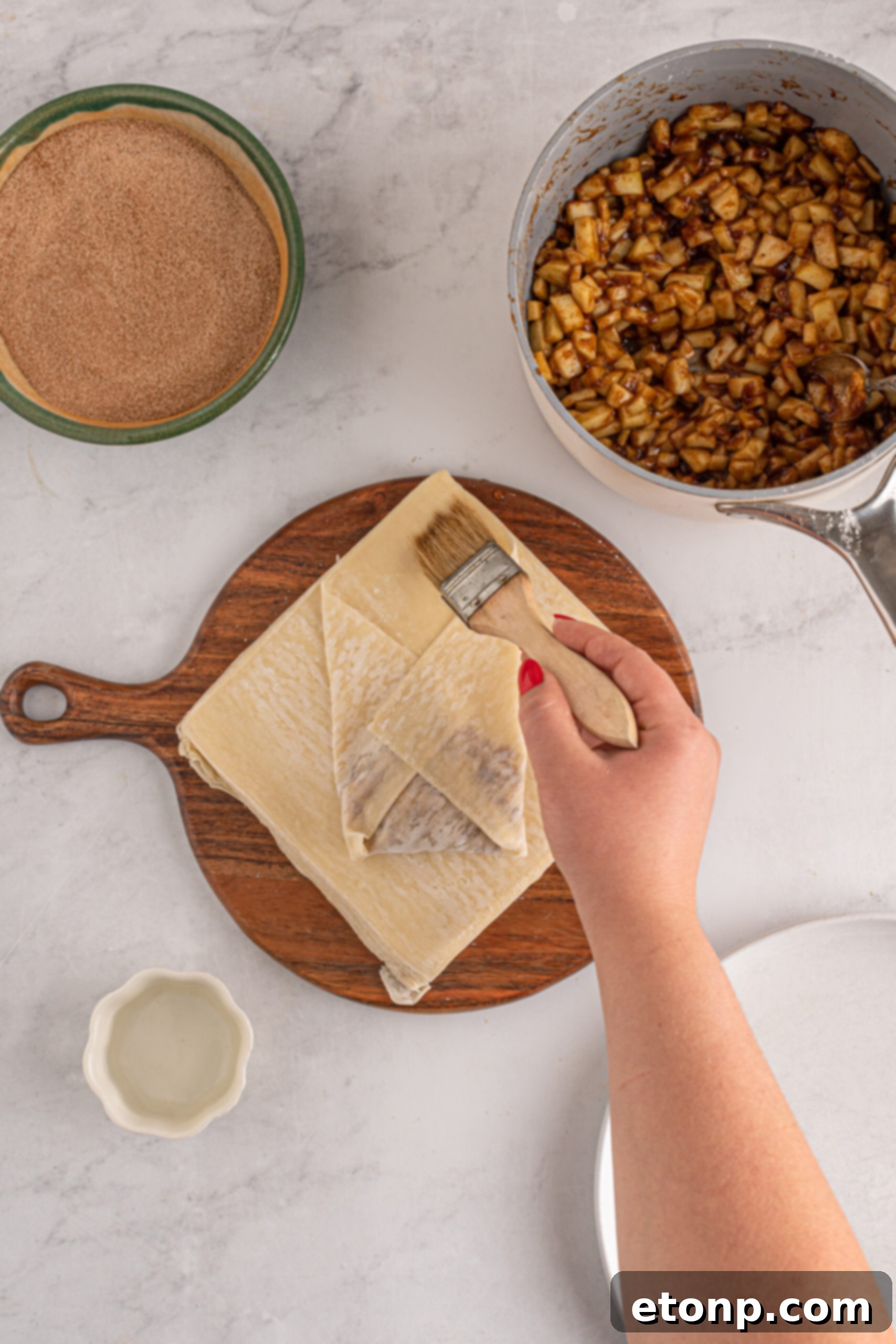 Another overhead perspective captures the meticulous step of folding and sealing apple pie egg rolls, emphasizing the hand-on preparation.