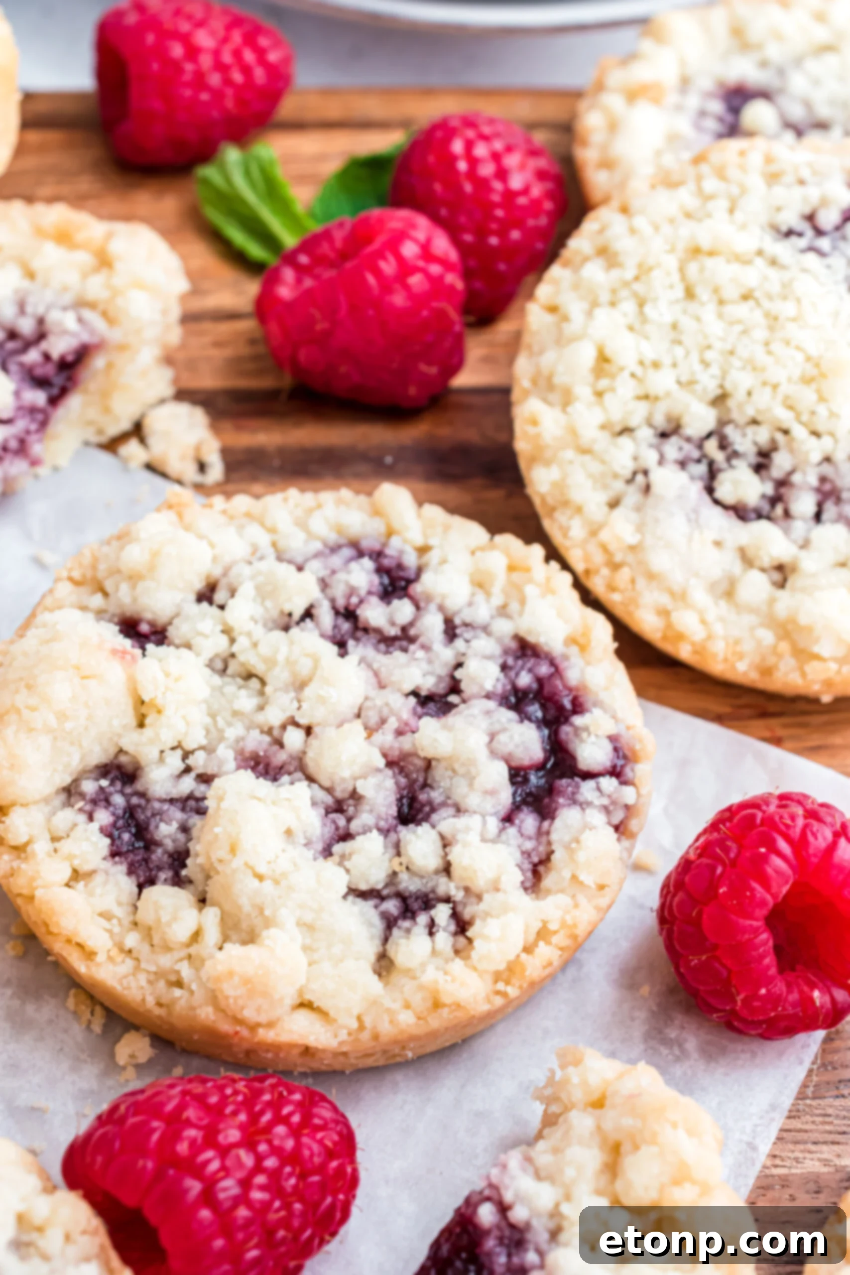 Raspberry cookies arranged artfully on a wooden cutting board.
