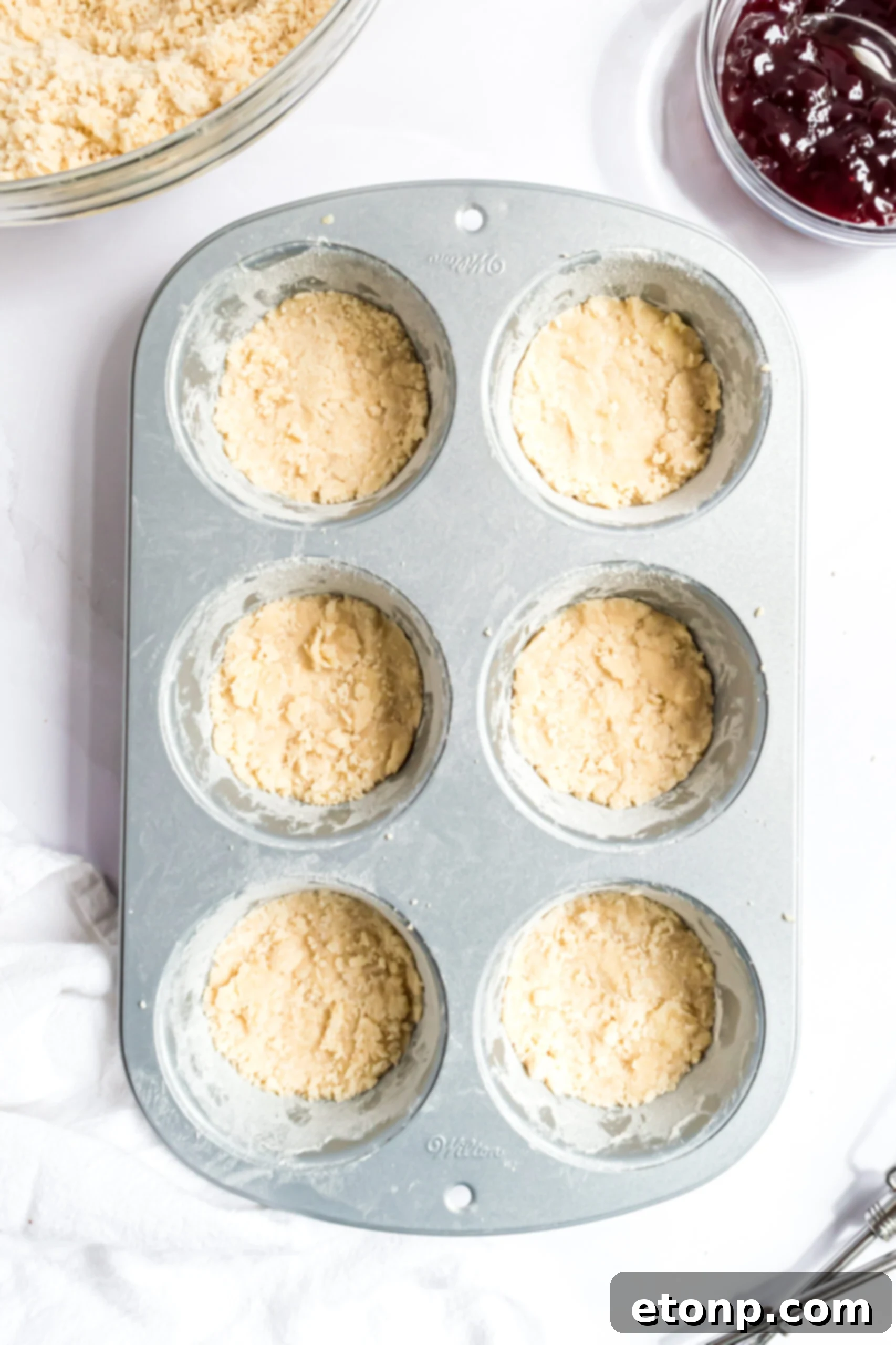 Overhead shot of the cookie crust being pressed into a muffin tin.
