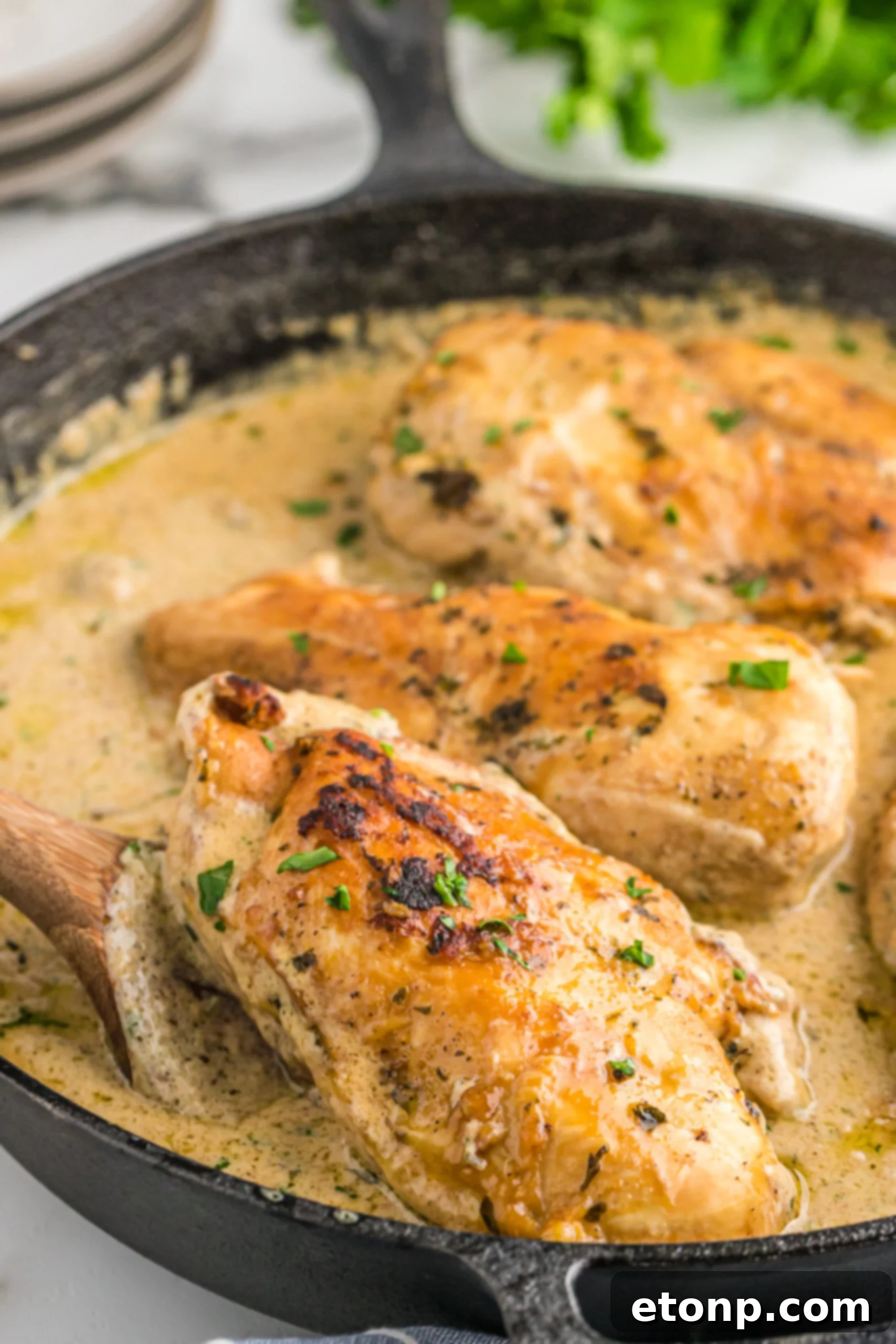 A piece of chicken being lifted from the cast iron skillet using a wooden spatula. 