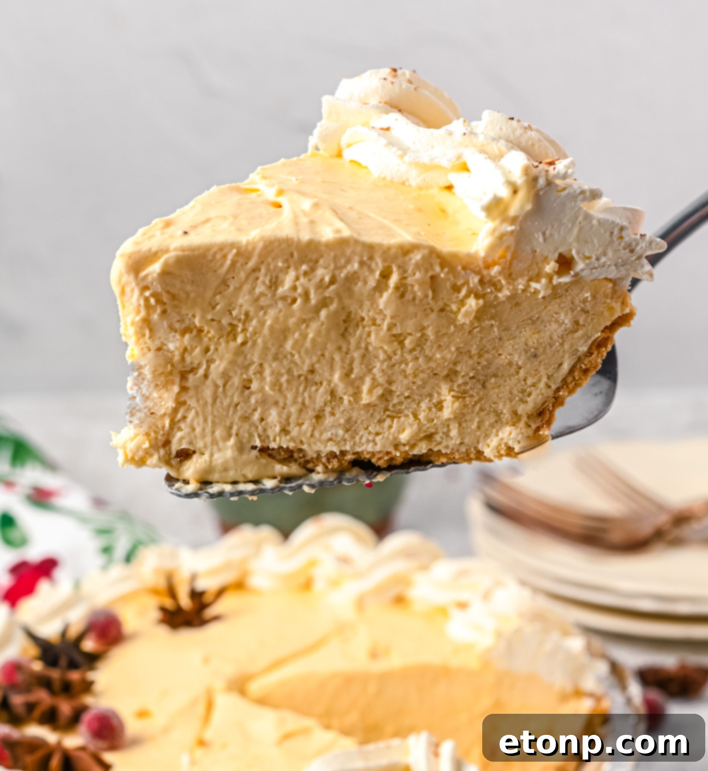 Velvety Eggnog Pie 11 A perfect slice of Eggnog Pie being gracefully lifted from the full pie with a silver pie spatula, showcasing its inviting layers and texture.