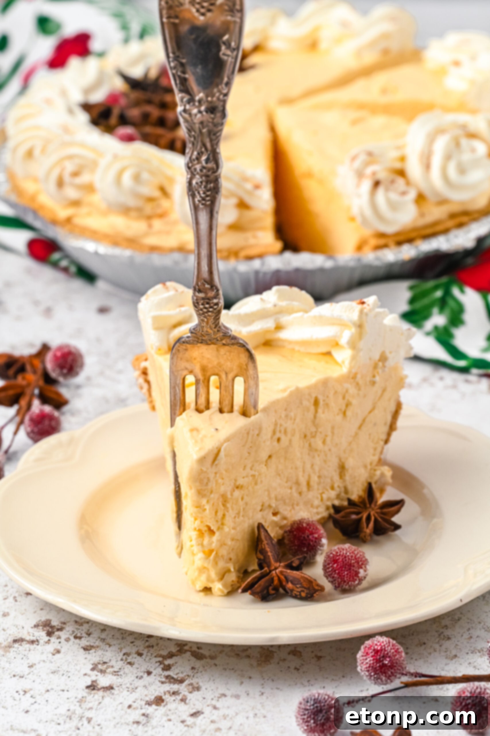 Velvety Eggnog Pie 10 A delectable piece of Eggnog Pie on a white dish, with a silver fork gently removing a perfect bite, highlighting its enticing layers.
