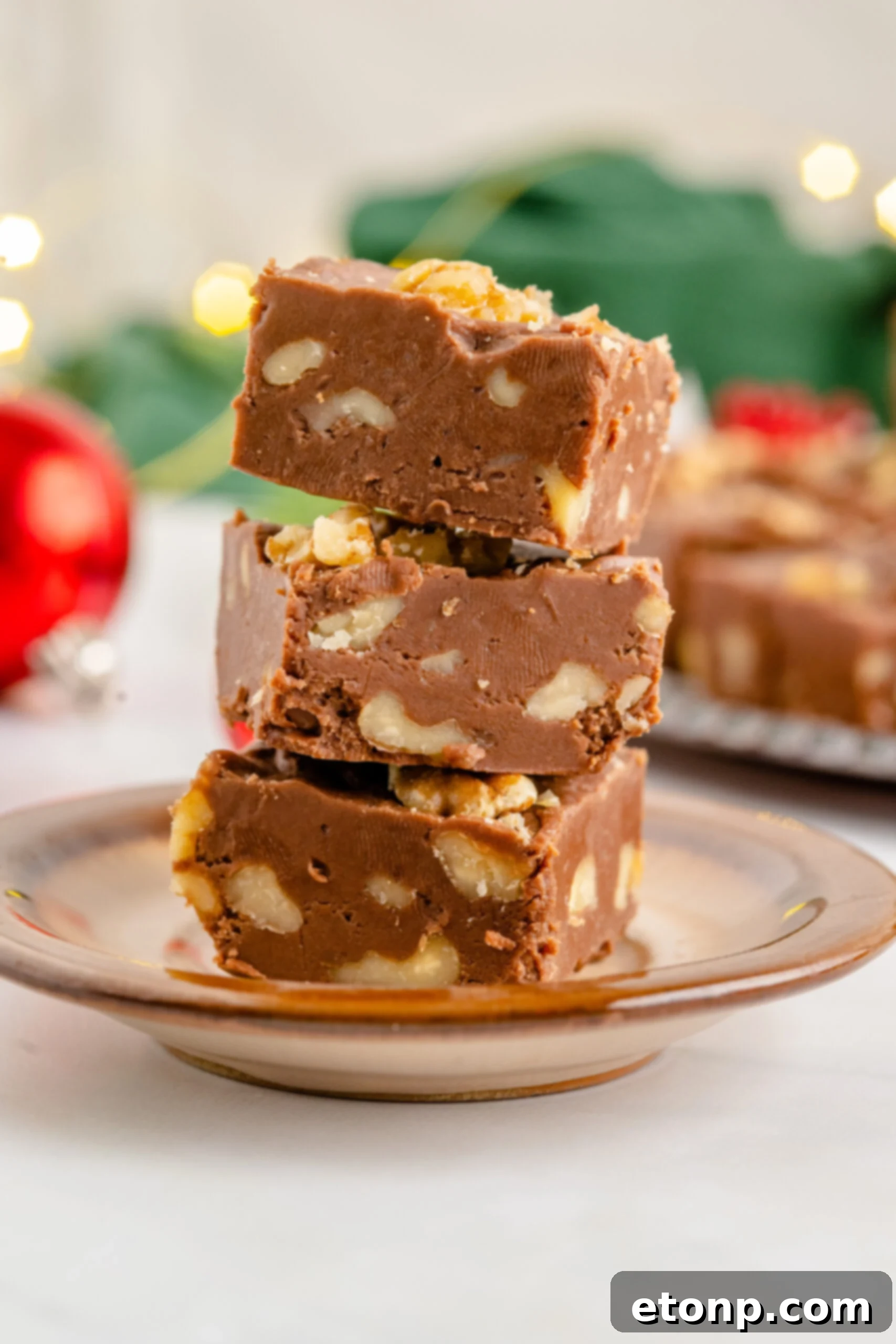 Three pieces of fudge stacked on a brown plate. 